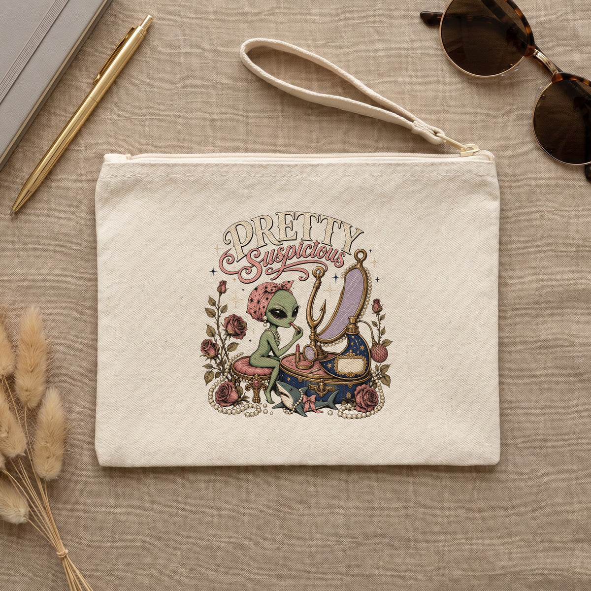 Clutch with "Pretty Suspicious" text and alien applying makeup, surrounded by roses and pearls.