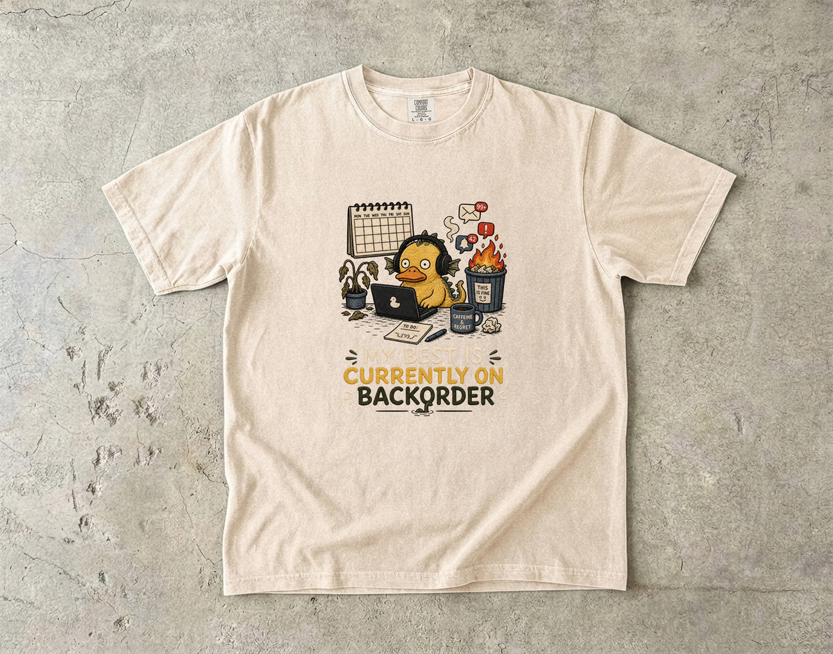 T-shirt with a cartoon duck at a desk, text reads "My Best Is Currently On Backorder".