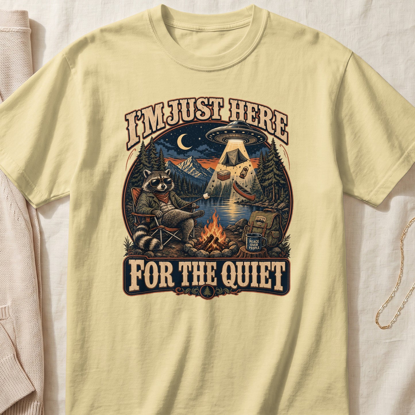T-shirt graphic of raccoon camping, UFO, and text "I'm Just Here For The Quiet".