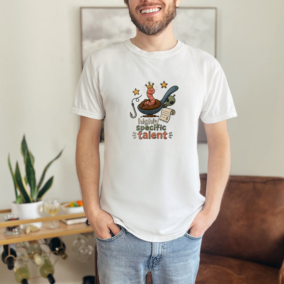 White t-shirt with cartoon worm wearing crown on spoon with alien and text "highly specific talent".