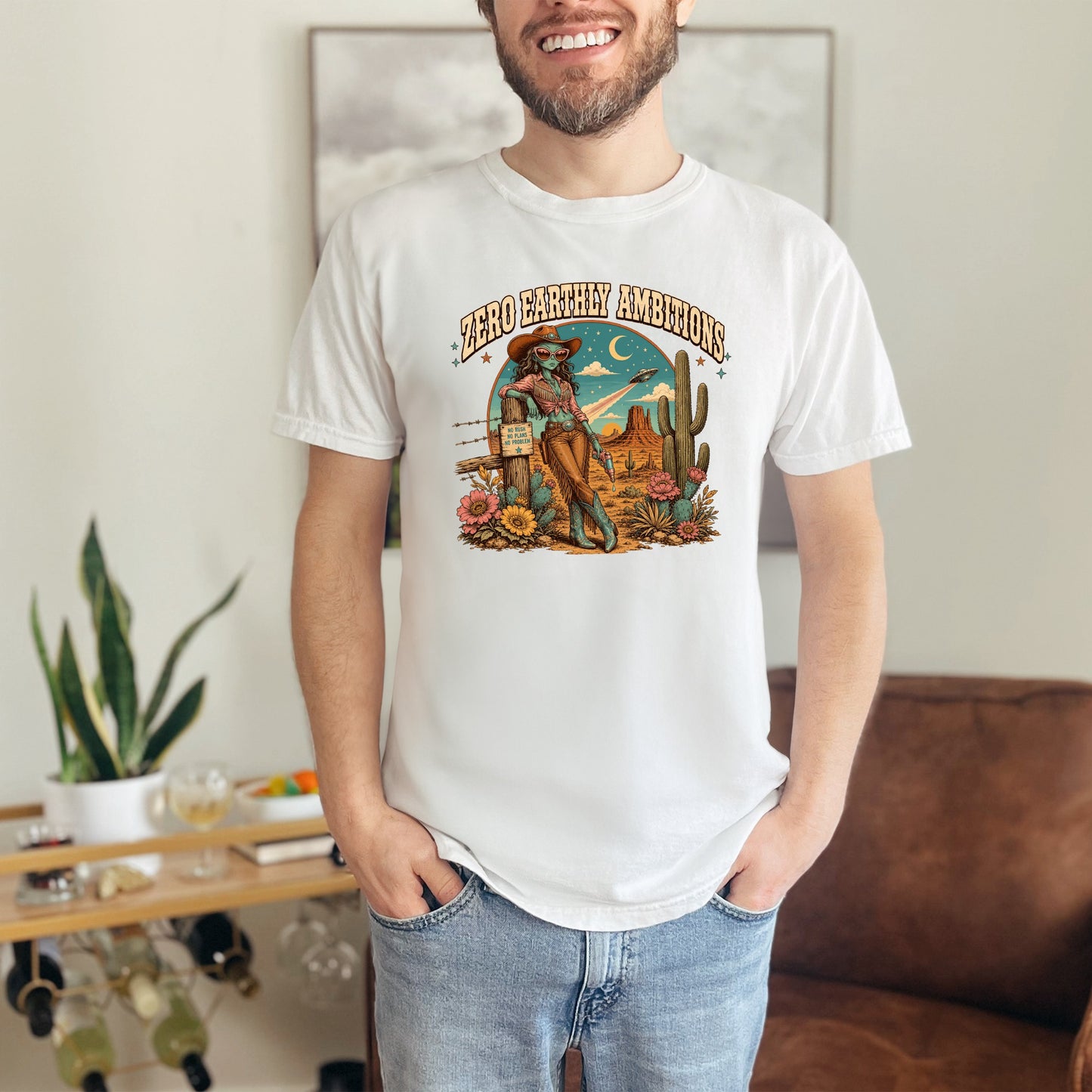White t-shirt with "Zero Earthly Ambitions" text and desert alien cowgirl graphic.