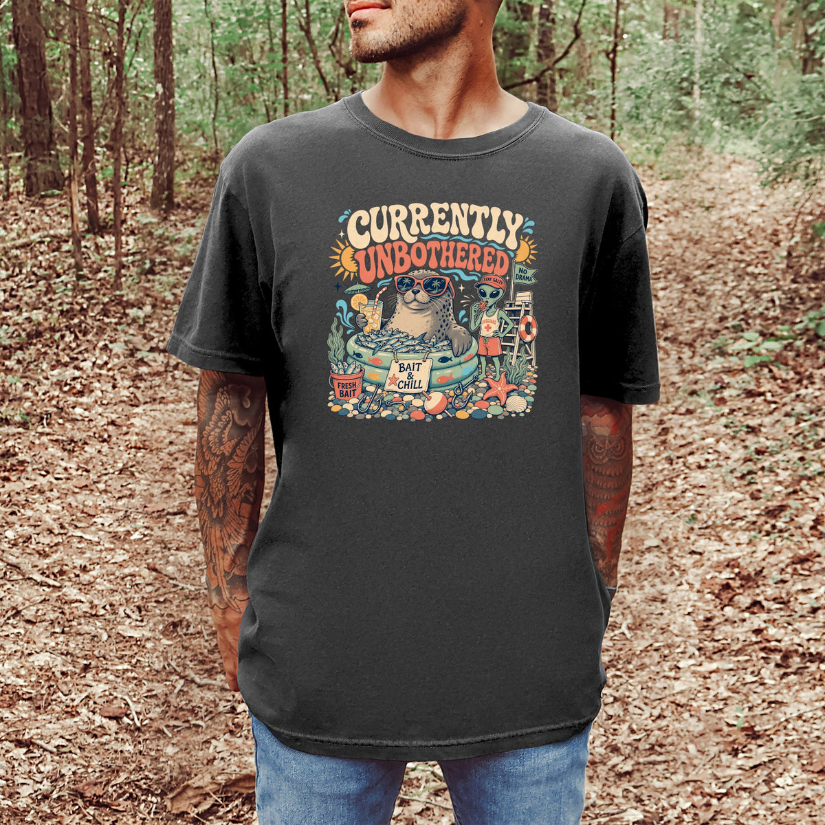 T-shirt graphic: "Currently Unbothered" with a seal and alien relaxing by water.