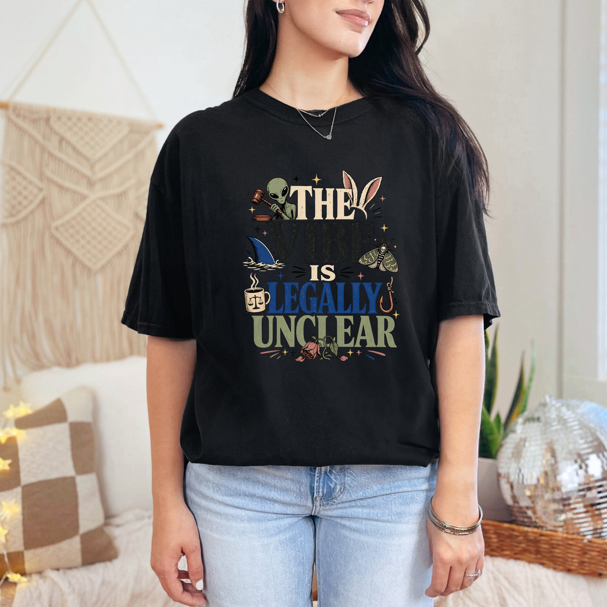 Black t-shirt with text "THE VIBE IS LEGALLY UNCLEAR" and graphic icons.