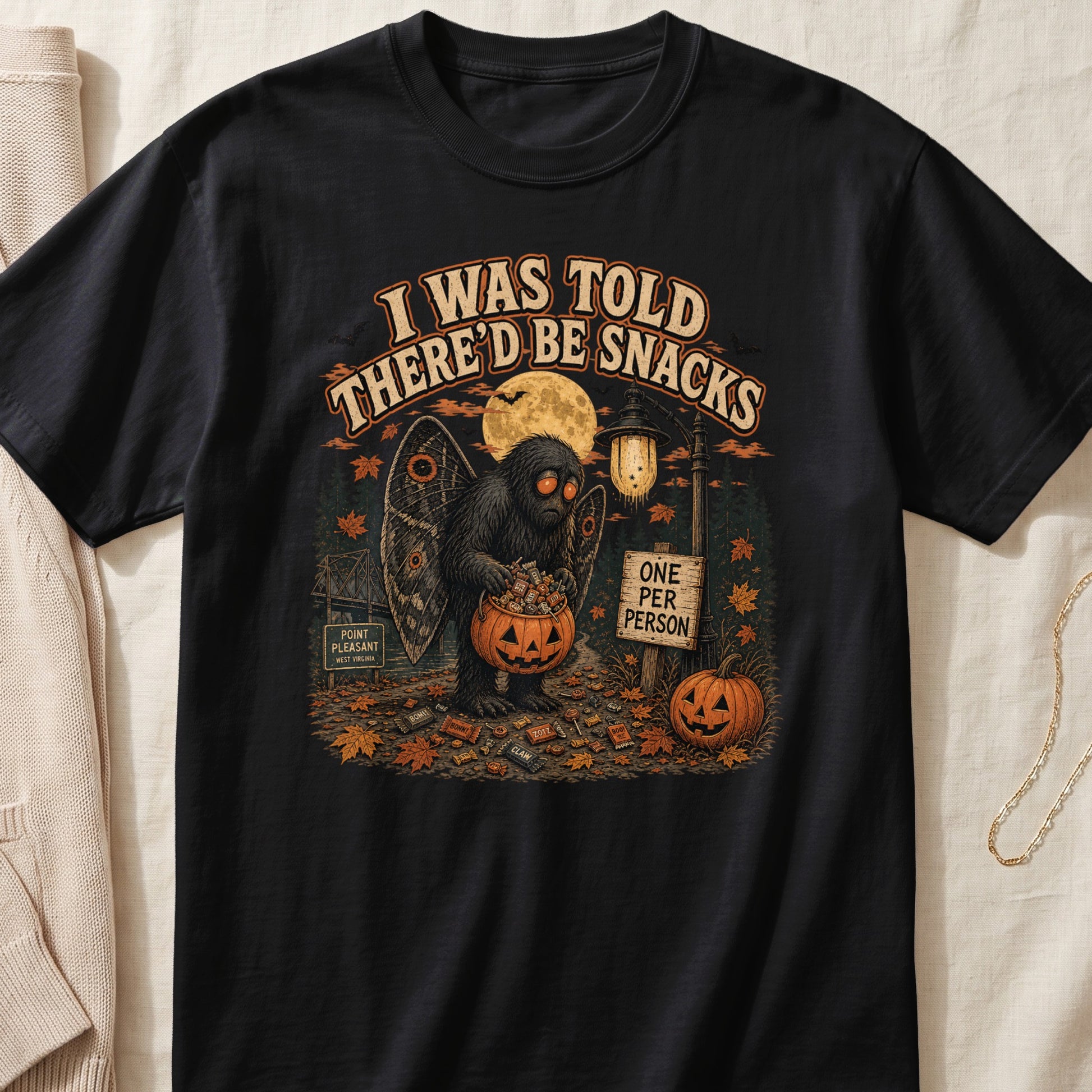 Mothman creature holds pumpkin candy bucket under moon, text "I WAS TOLD THERE'D BE SNACKS".
