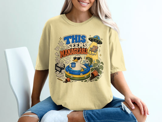 Yellow t-shirt graphic with text "THIS SEEMS MANAGEABLE" and a duck in a pool.