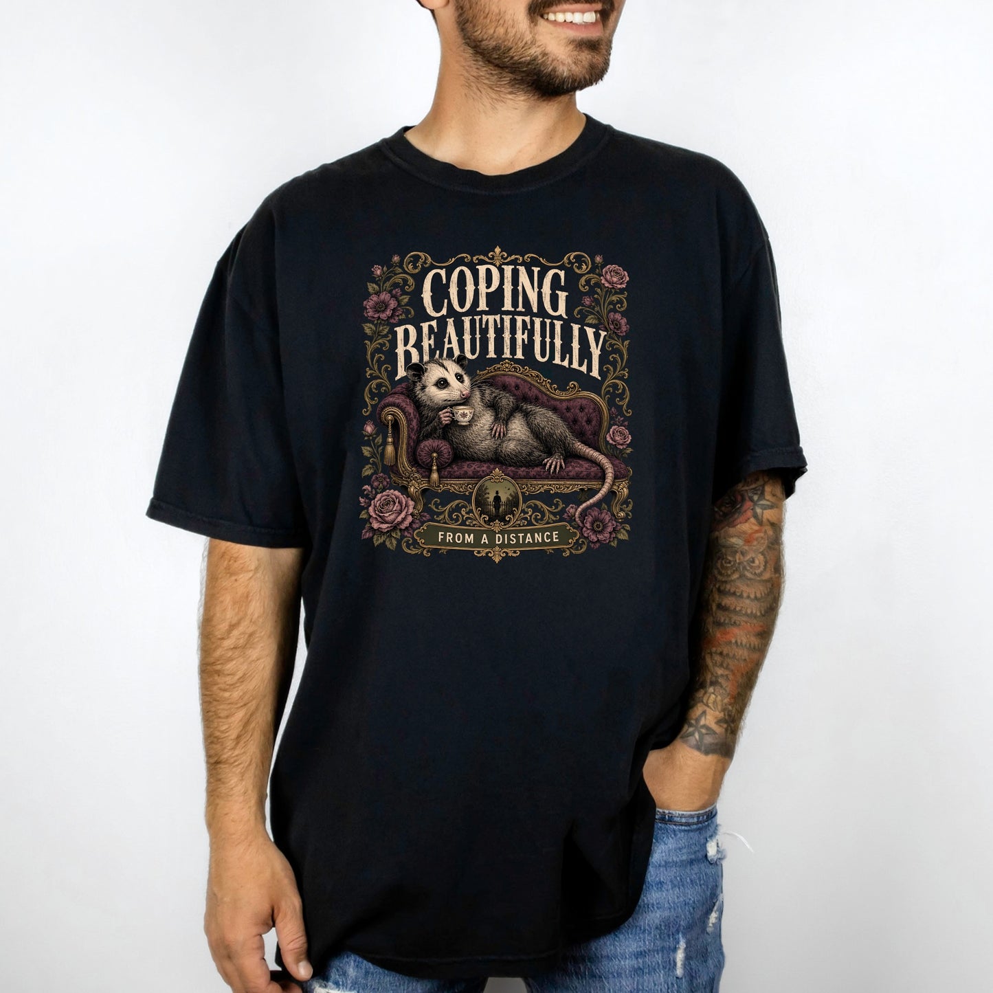 Black t-shirt with opossum on couch, text "COPING BEAUTIFULLY FROM A DISTANCE".
