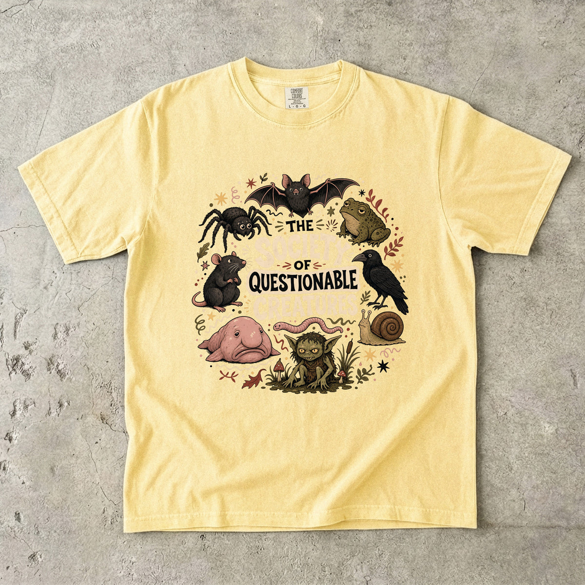 Yellow t-shirt with "The Society of Questionable Creatures" graphic featuring various creatures.