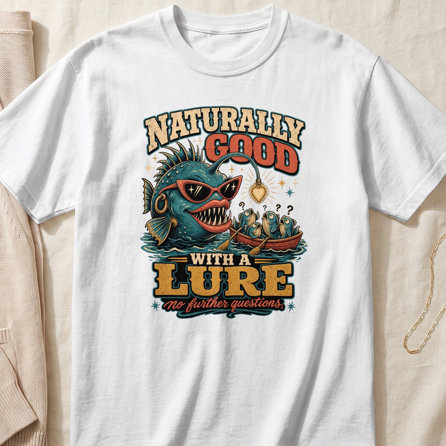 T-shirt graphic: a cartoon anglerfish with sunglasses and a light lure, and a boat of confused fish.