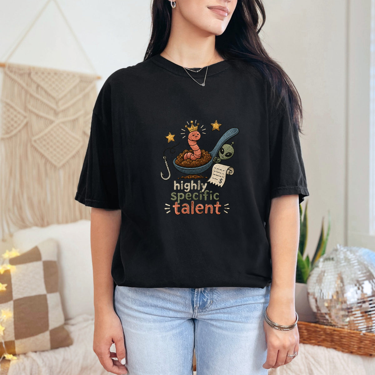 Black t-shirt with a spoon graphic featuring a worm, alien, and receipt, with text "highly specific talent".