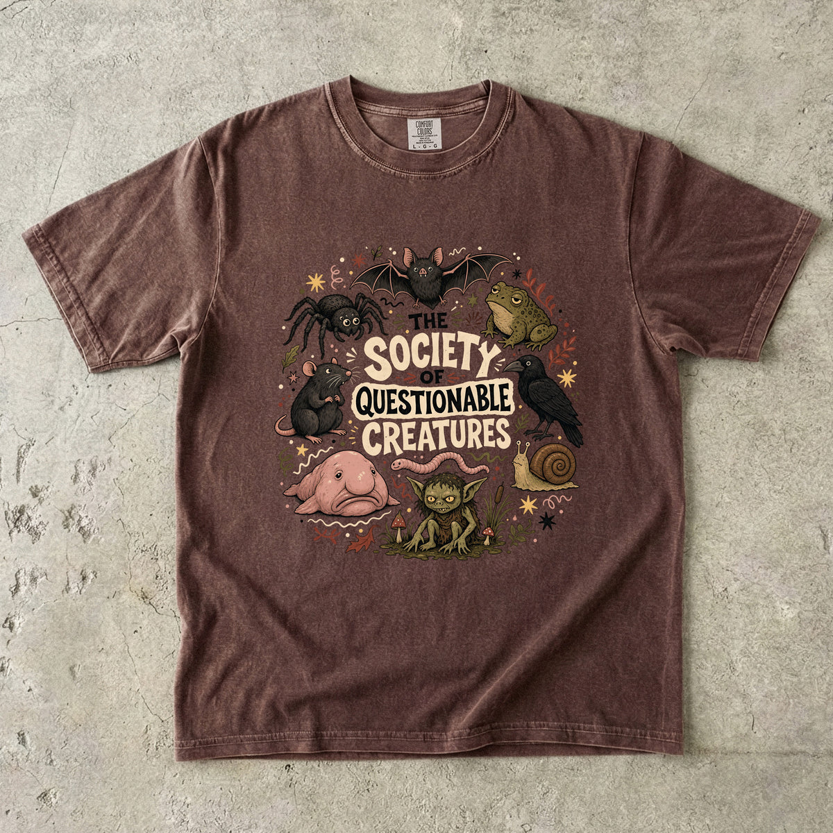 Brown t-shirt with "The Society of Questionable Creatures" graphic.