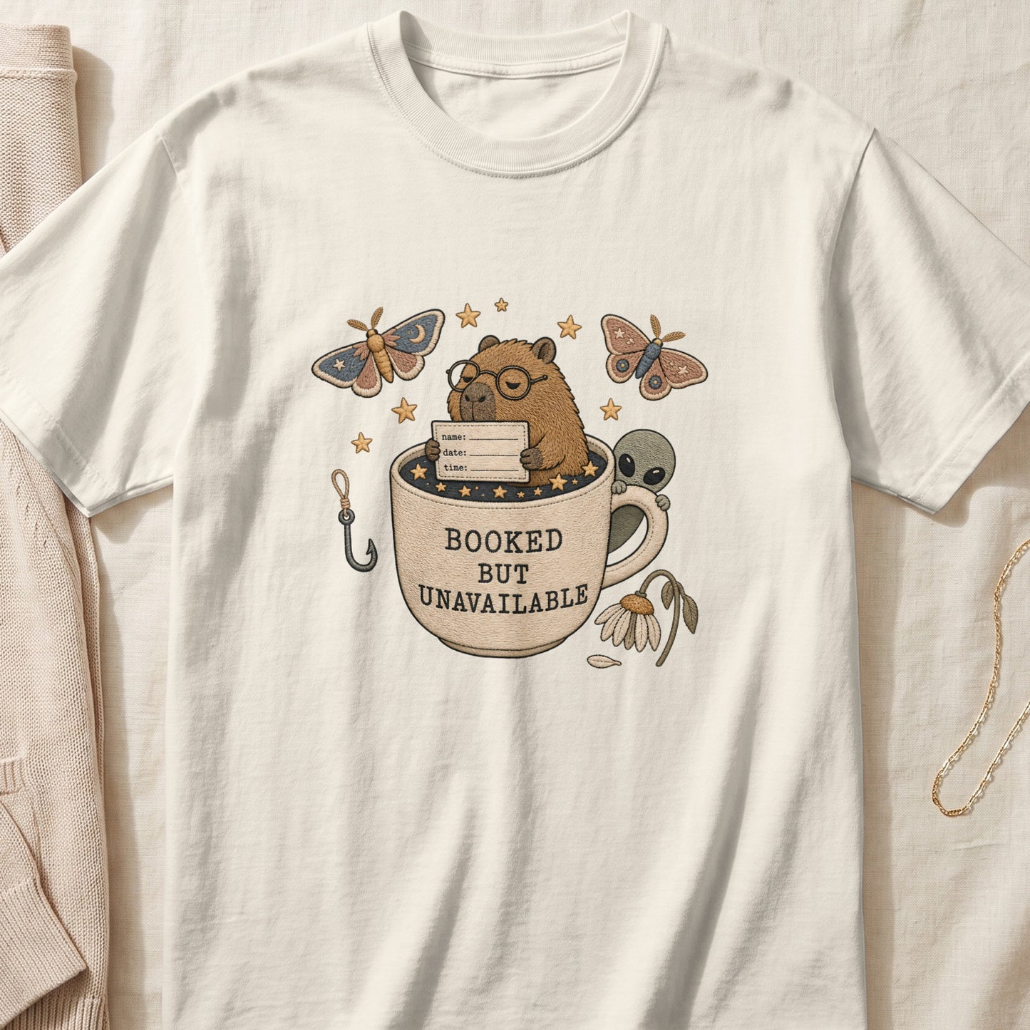 Capybara in coffee cup with alien, moths, and text "BOOKED BUT UNAVAILABLE".