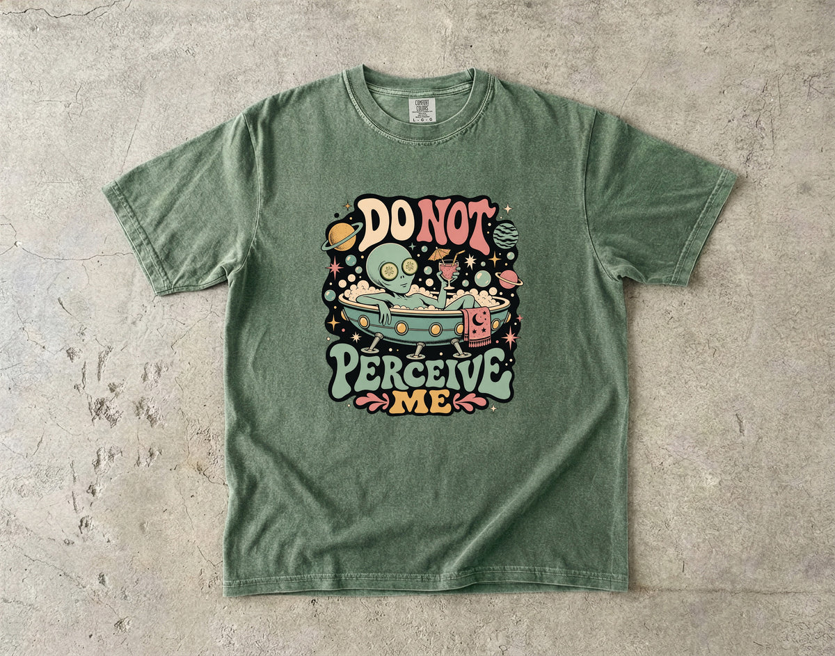 Green t-shirt with a graphic of an alien in a bathtub saying "DO NOT PERCEIVE ME".