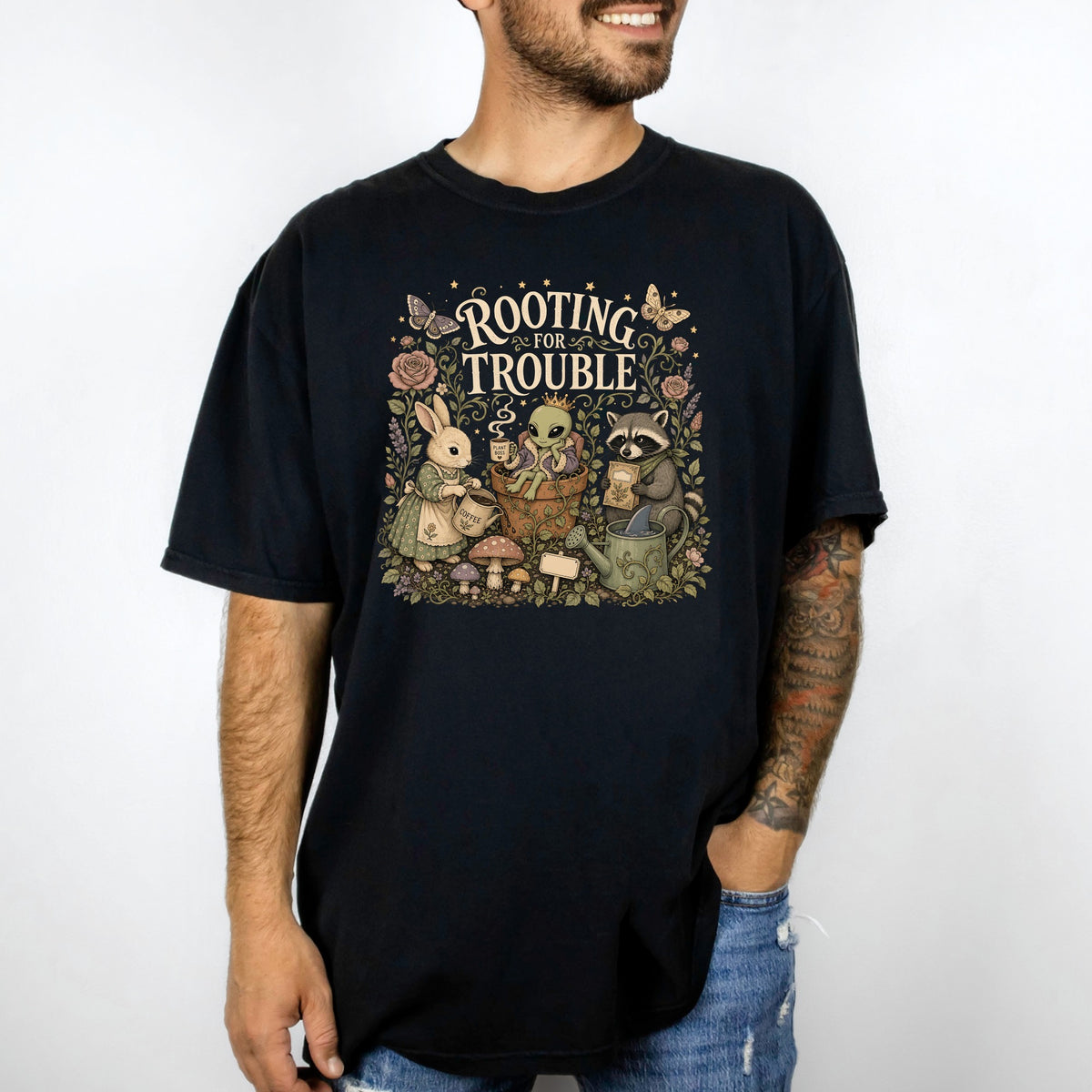 Black t-shirt with "Rooting for Trouble" text and illustrated rabbit, alien, and raccoon characters.