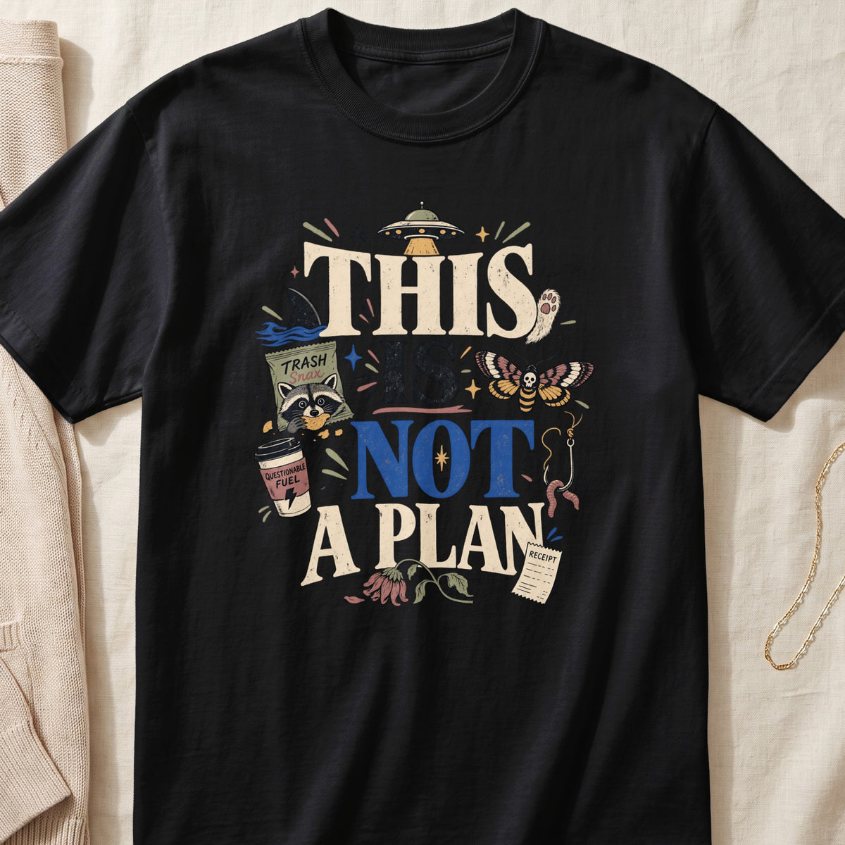 Black t-shirt with text "THIS IS NOT A PLAN" and graphic elements.