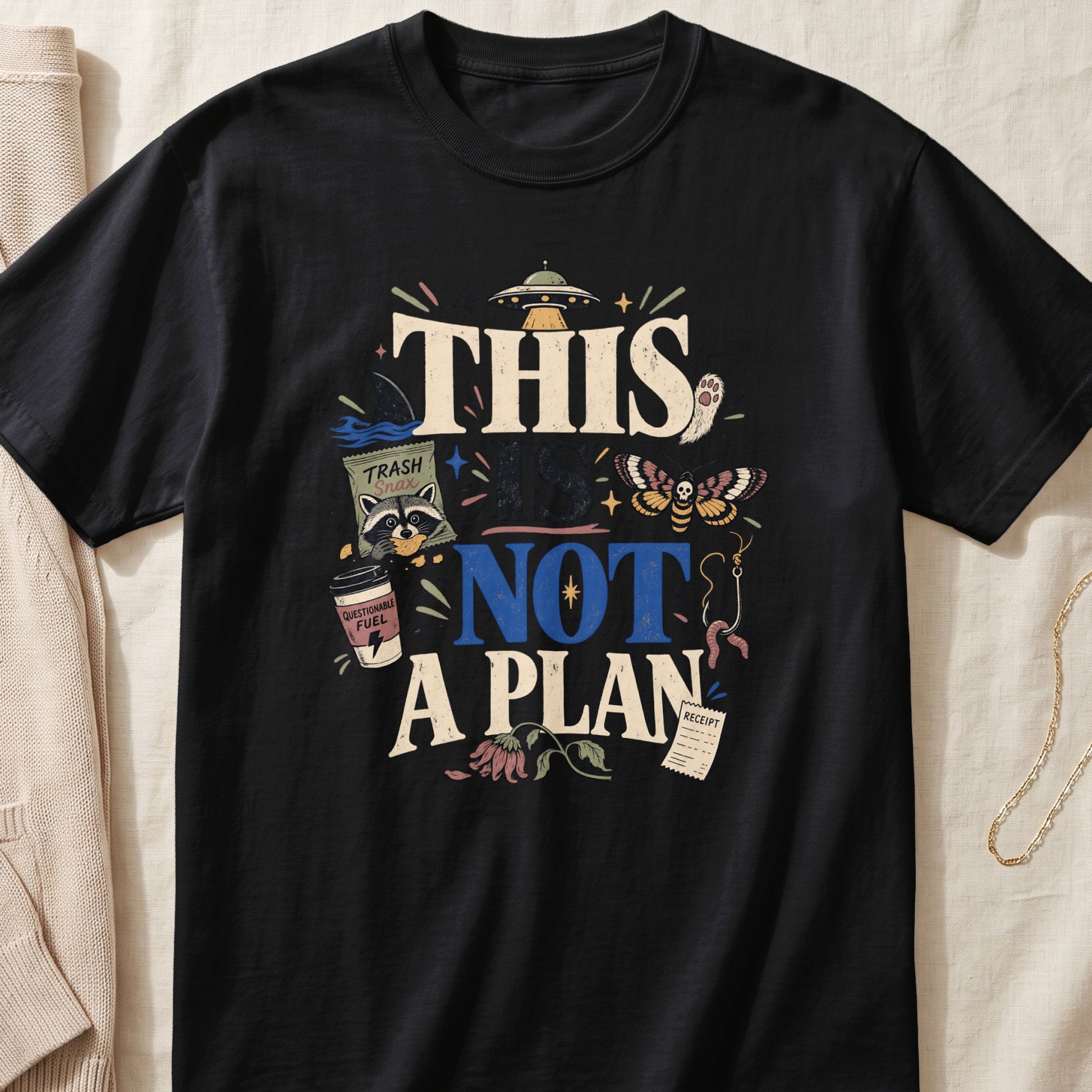 Black t-shirt with text "THIS IS NOT A PLAN" and graphic elements.