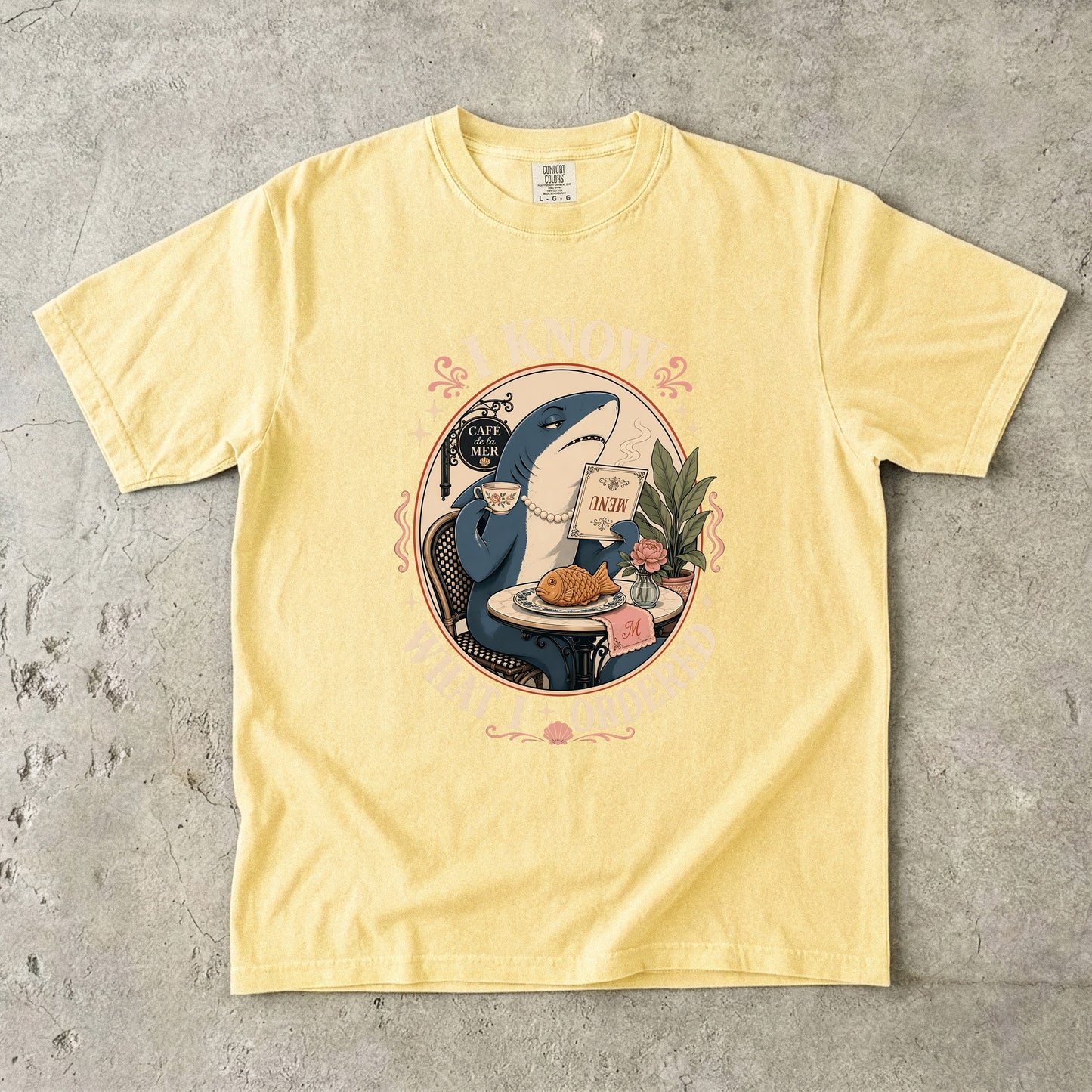 Yellow t-shirt with graphic of a shark at Cafe de la Mer ordering food.
