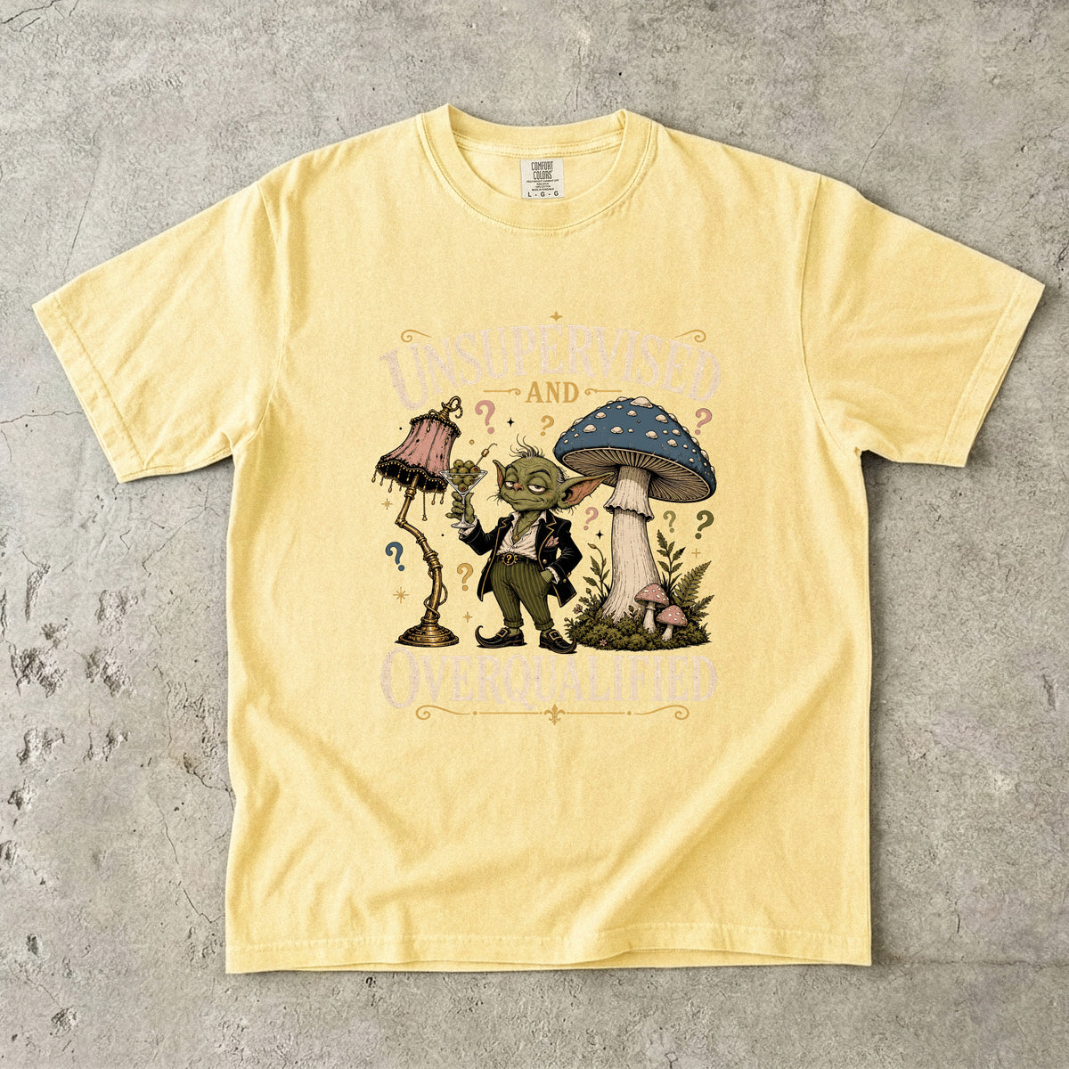 Yellow t-shirt with text "Unsupervised and Overqualified" and a goblin character.