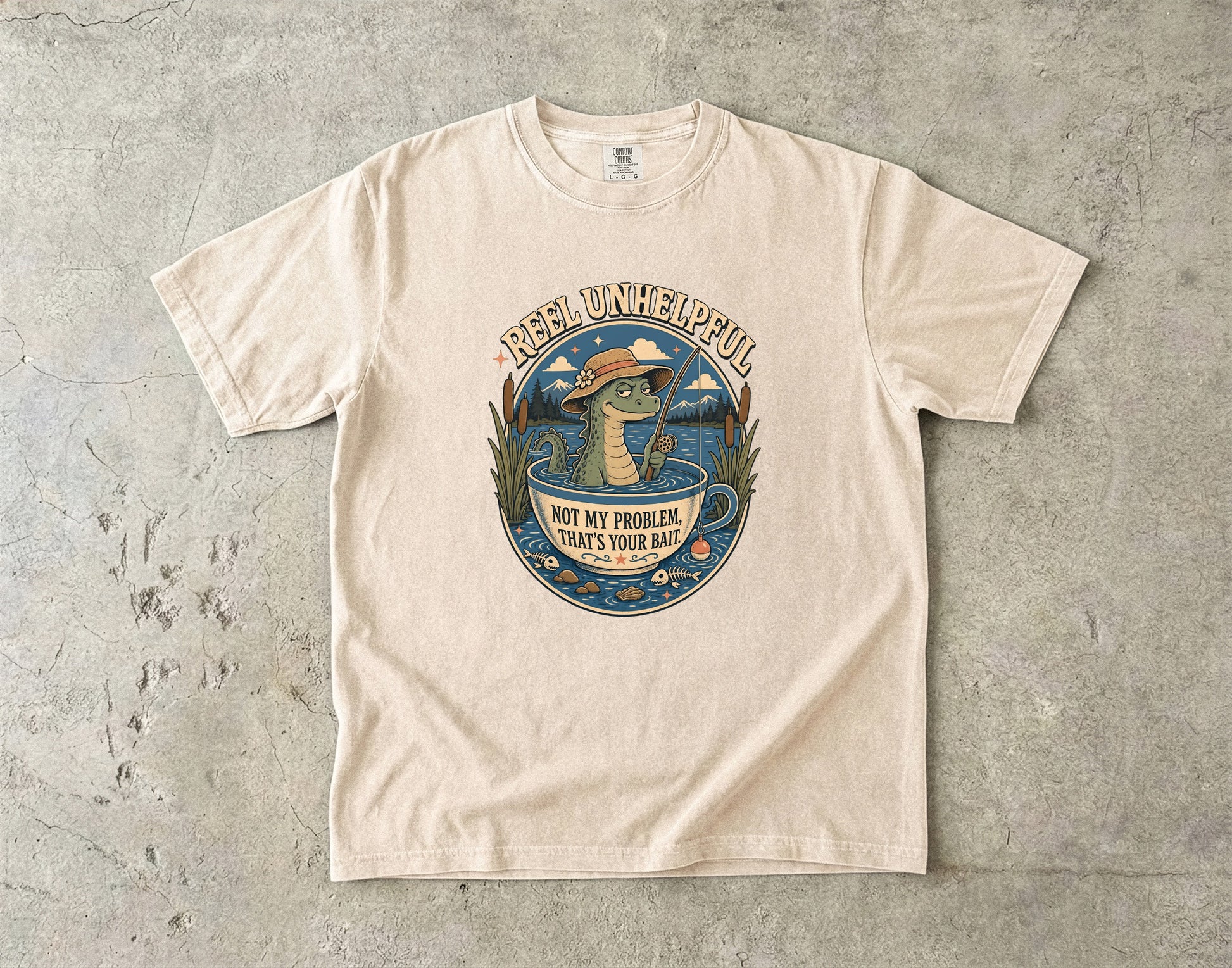 T-shirt with a cartoon alligator fishing in a teacup, "Reel Unhelpful" text.