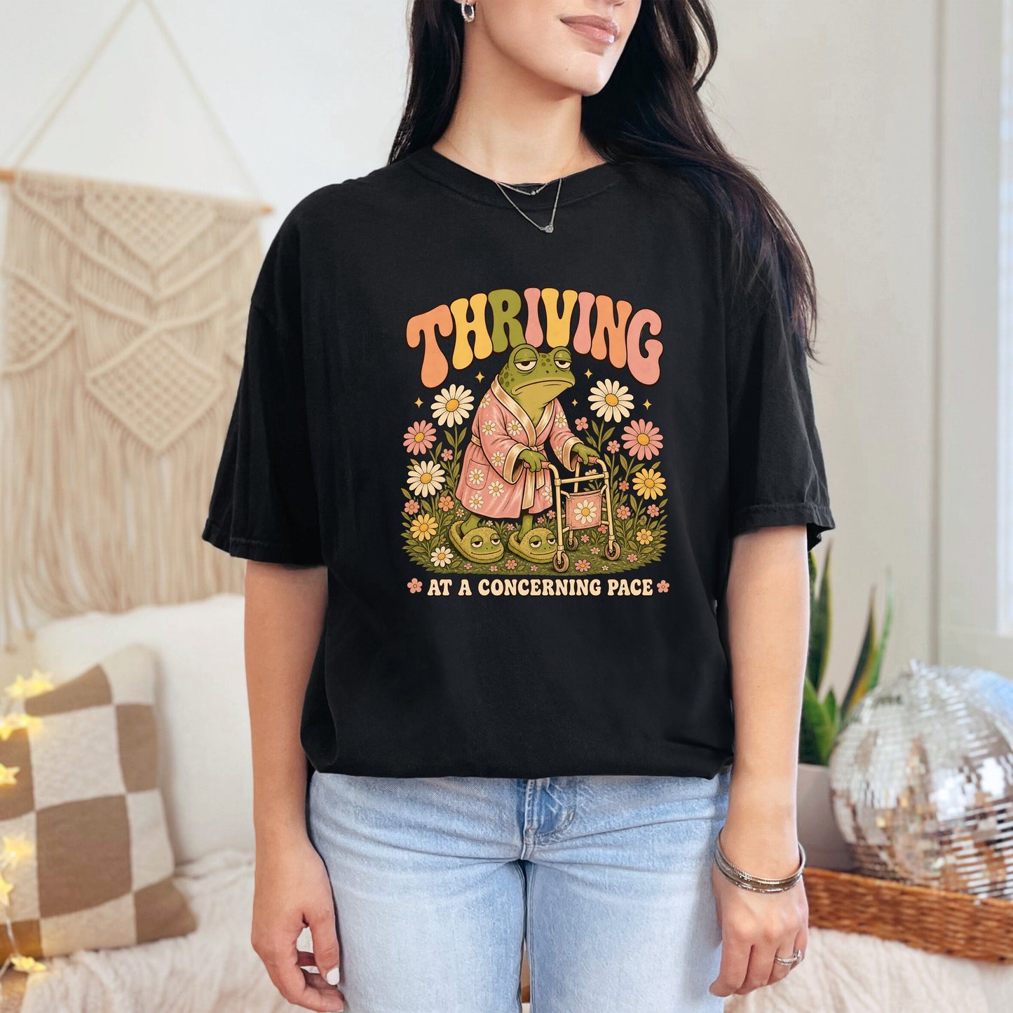T-shirt with retro graphic of a frog with walker and text "Thriving at a concerning pace."