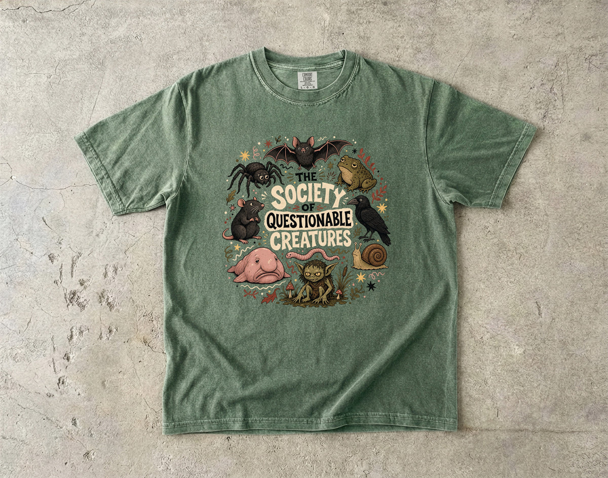 Green t-shirt with "The Society of Questionable Creatures" text and various odd animals.