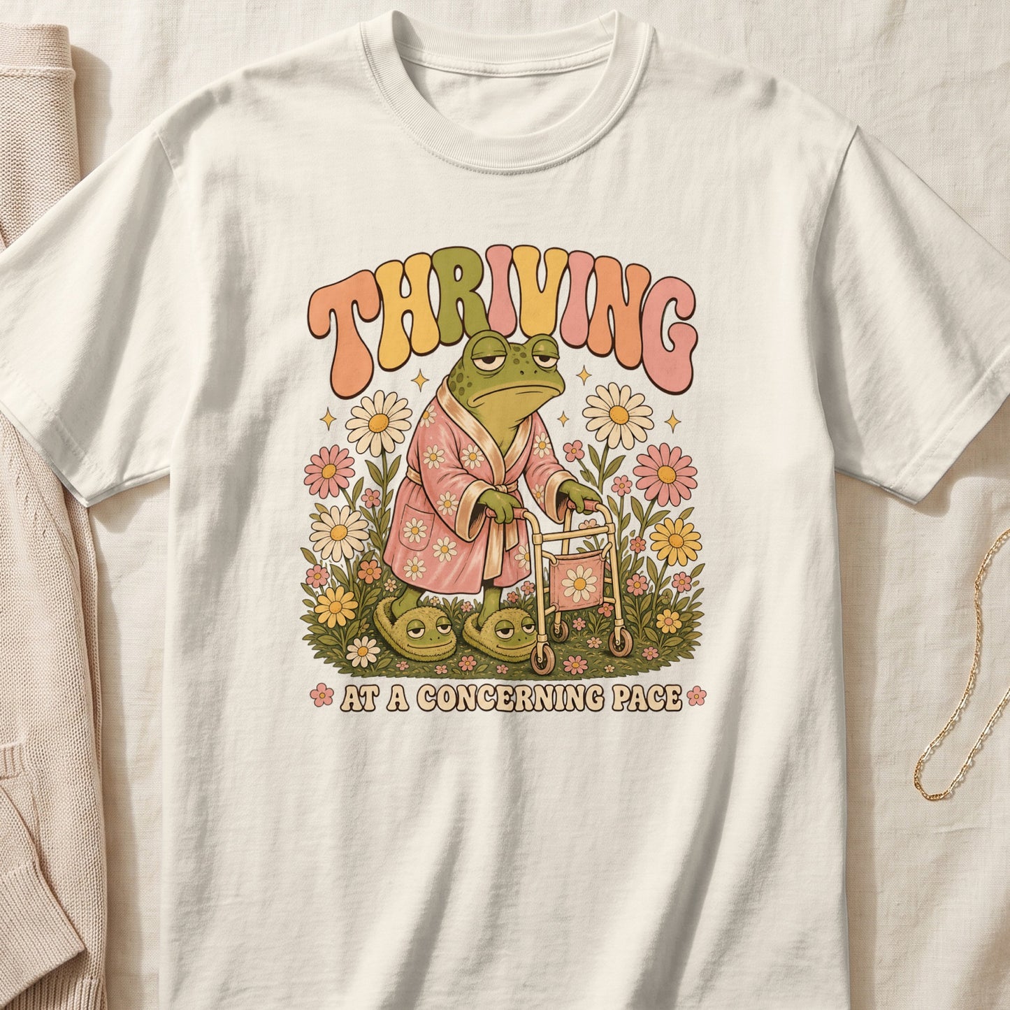 Retro frog in robe and slippers with walker, surrounded by flowers, says "THRIVING AT A CONCERNING PACE".