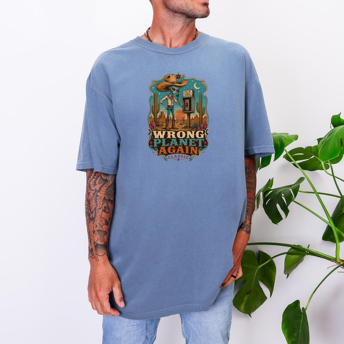 T-shirt with graphic of alien in cowboy hat talking on payphone in desert scene.