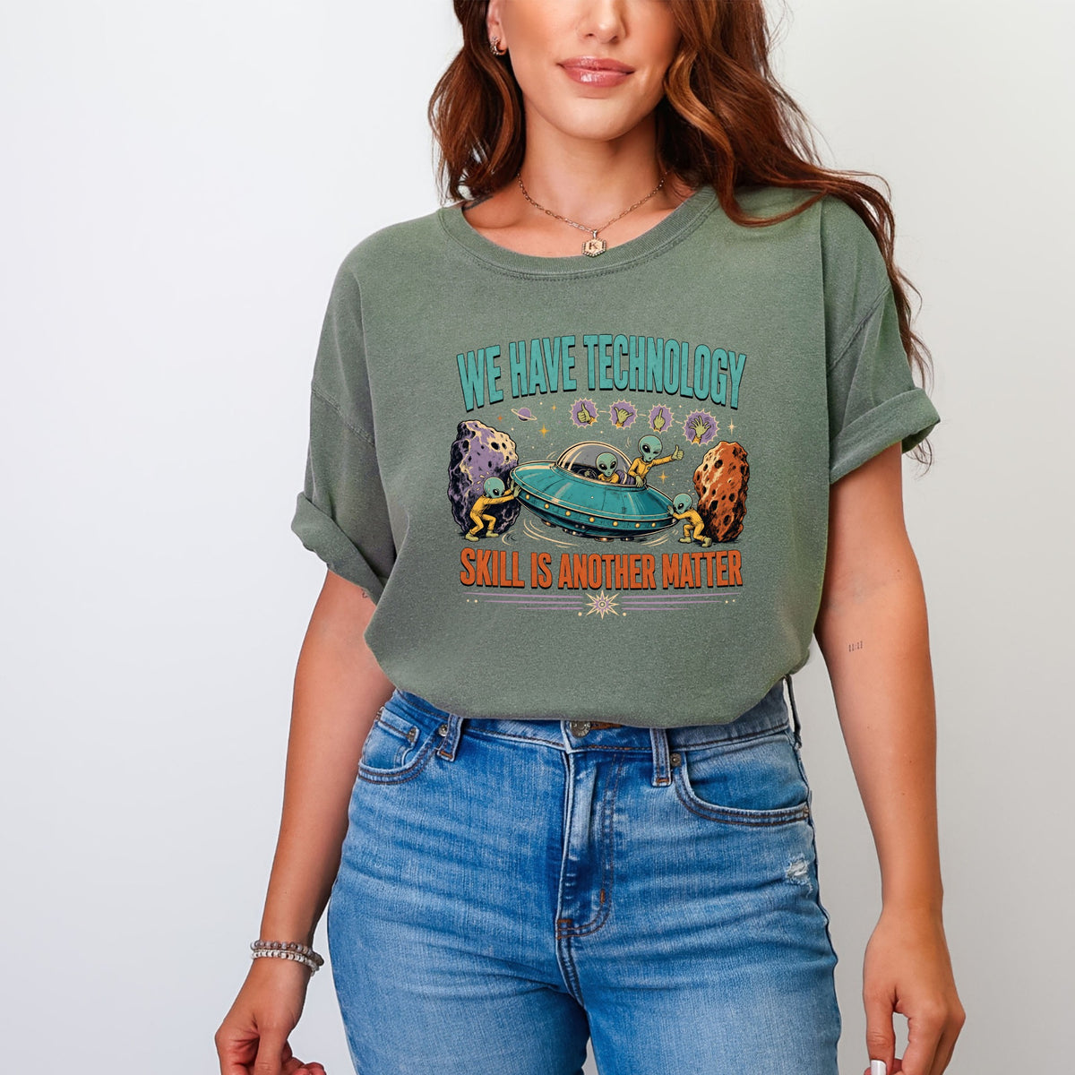 Green t-shirt with "WE HAVE TECHNOLOGY SKILL IS ANOTHER MATTER" and aliens in a UFO.