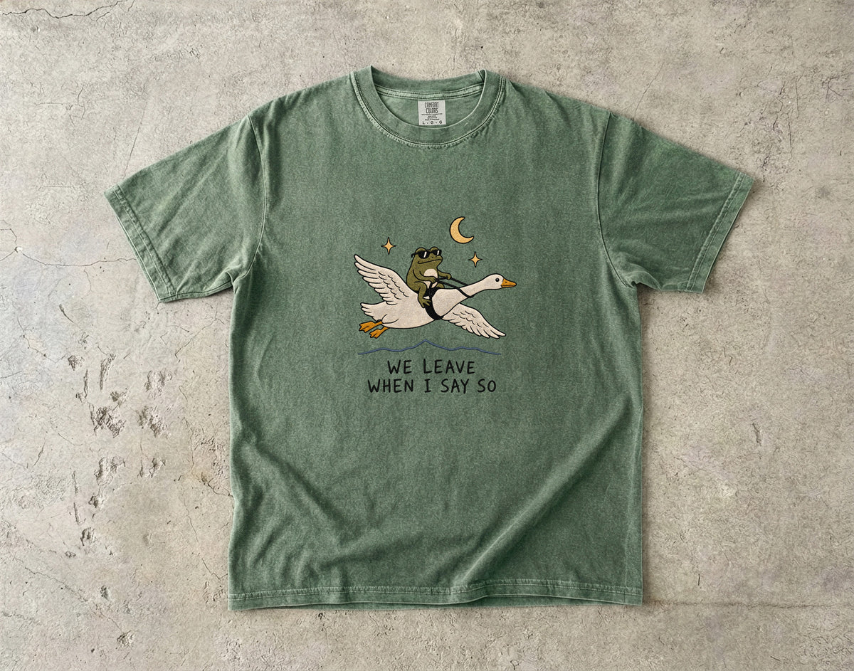 Green t-shirt with frog riding a goose under a crescent moon.