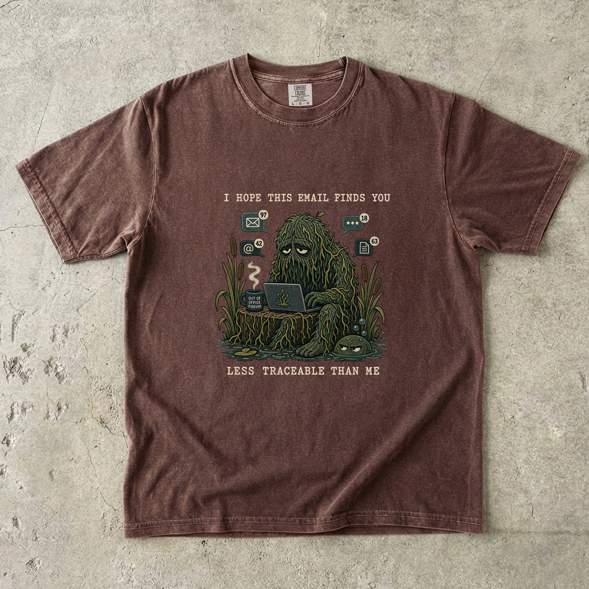 T-shirt graphic of a swamp monster with a laptop and text "I HOPE THIS EMAIL FINDS YOU LESS TRACEABLE THAN ME".