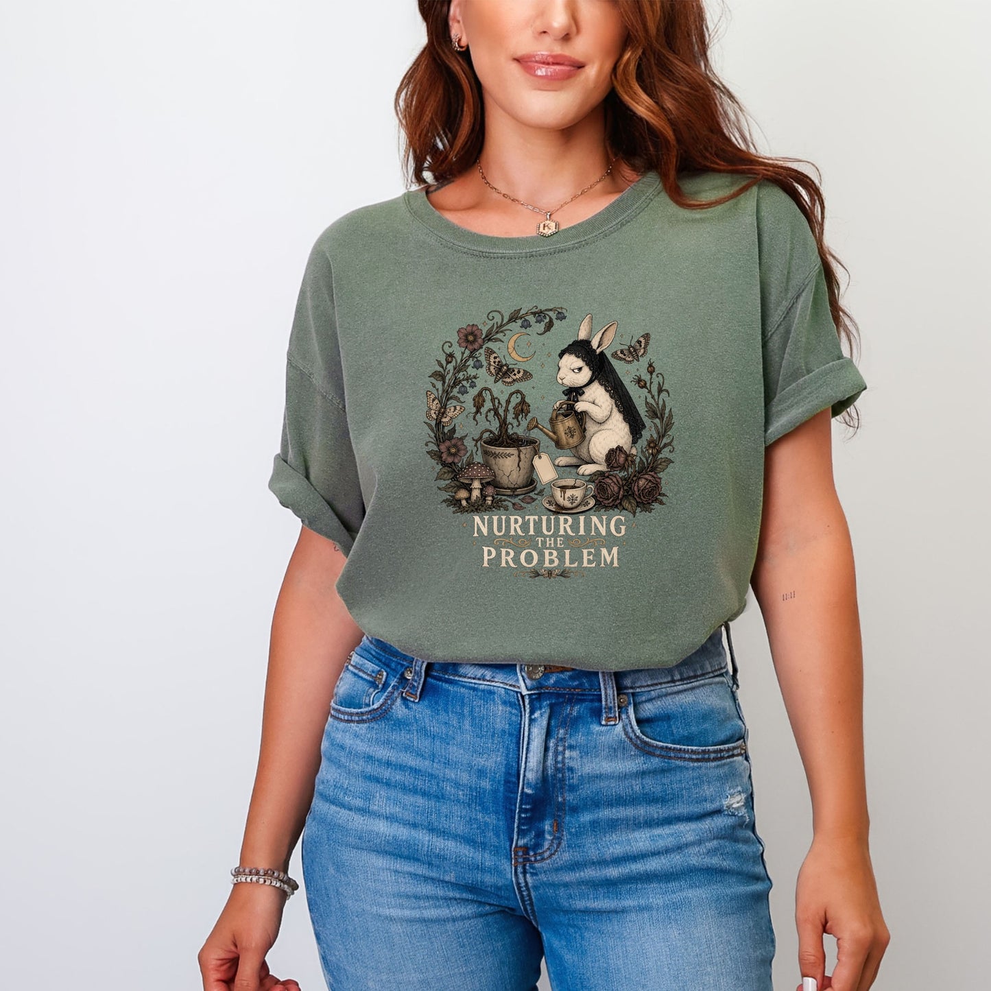 A woman wearing a faded green t-shirt with a vintage rabbit graphic and text reading NURTURING THE PROBLEM.