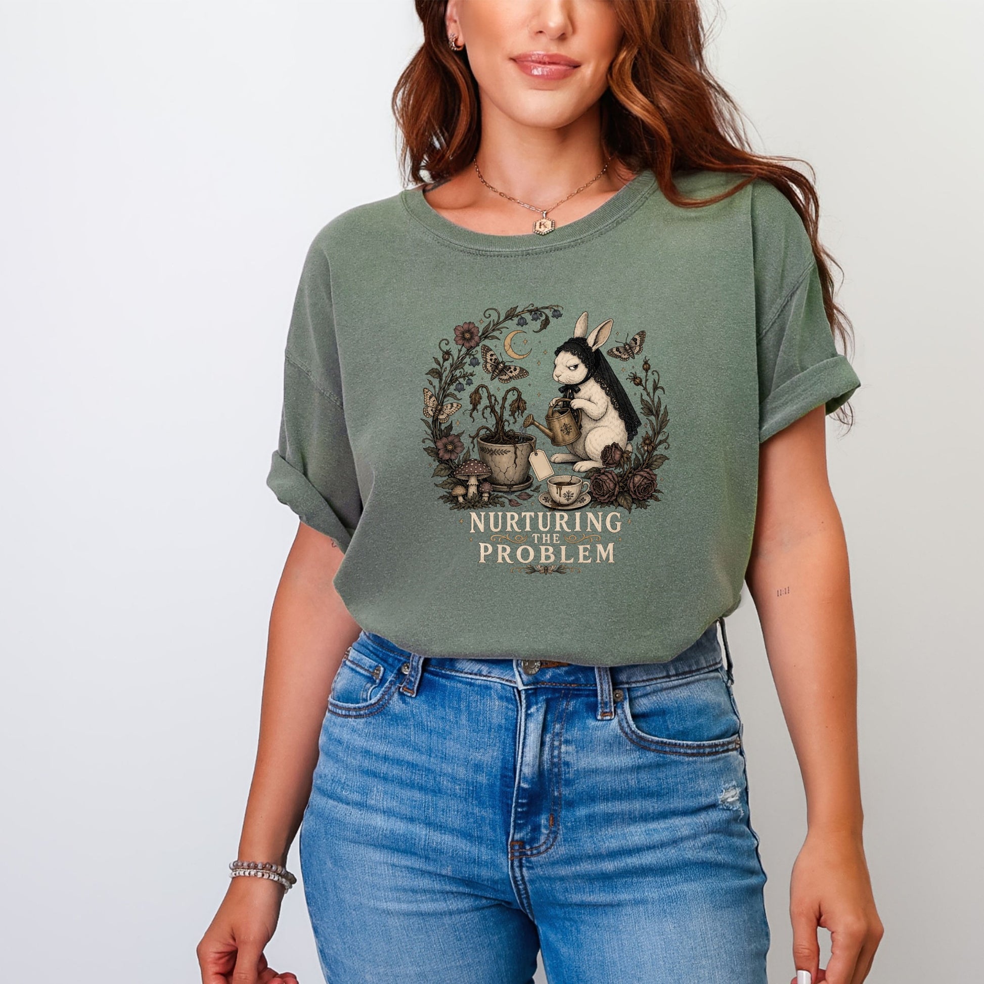 A woman wearing a faded green t-shirt with a vintage rabbit graphic and text reading NURTURING THE PROBLEM.