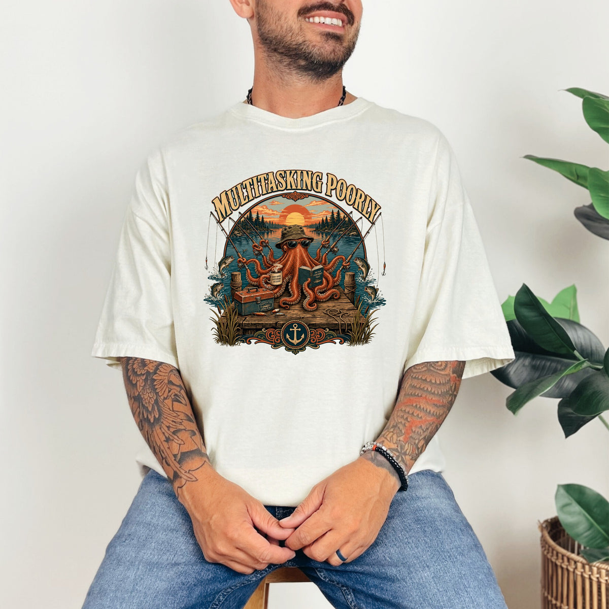 T-shirt graphic with octopus fishing, "Multitasking Poorly" text, and sunset scene.