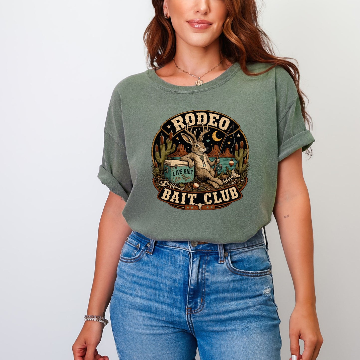 T-shirt graphic with a rabbit wearing antlers, fishing, and text "Rodeo Bait Club".