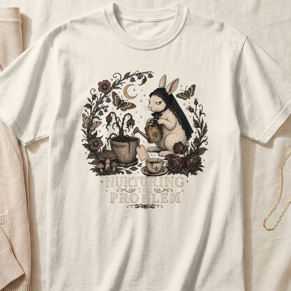 Off-white t-shirt featuring a vintage illustration of a rabbit watering a dead plant, with the text nurturing the problem.