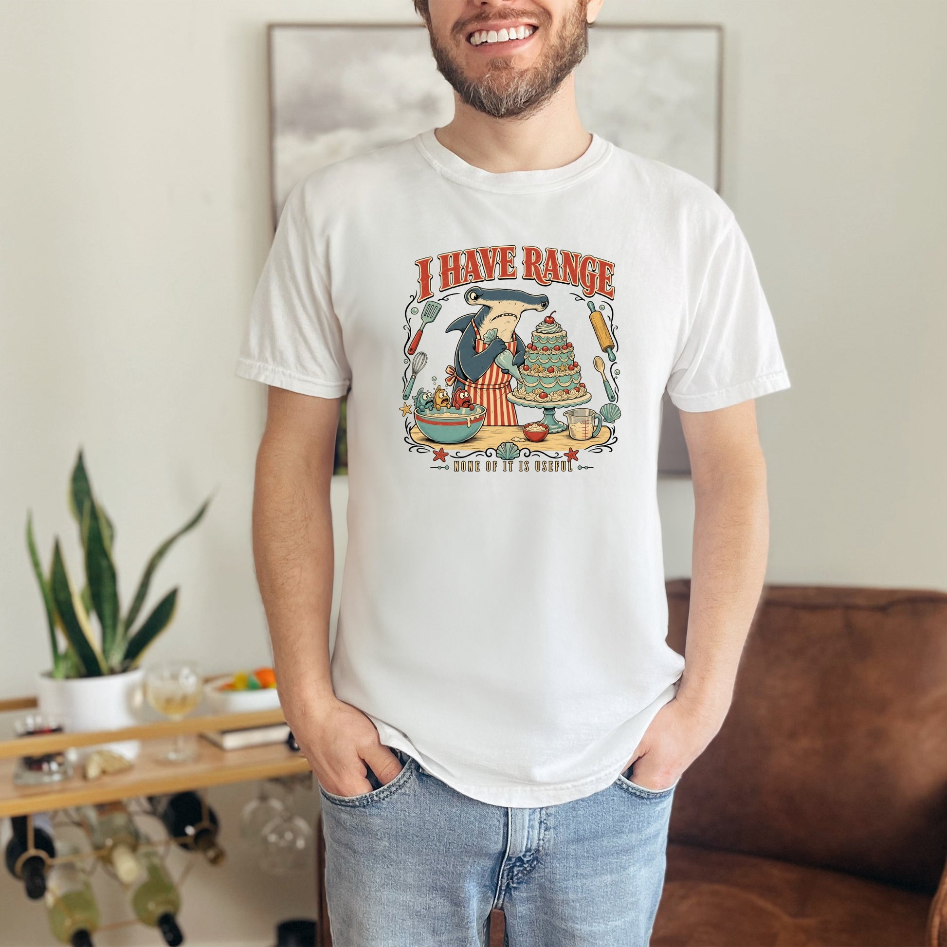 White t-shirt with graphic of shark baking a cake with text "I HAVE RANGE NONE OF IT IS USEFUL."