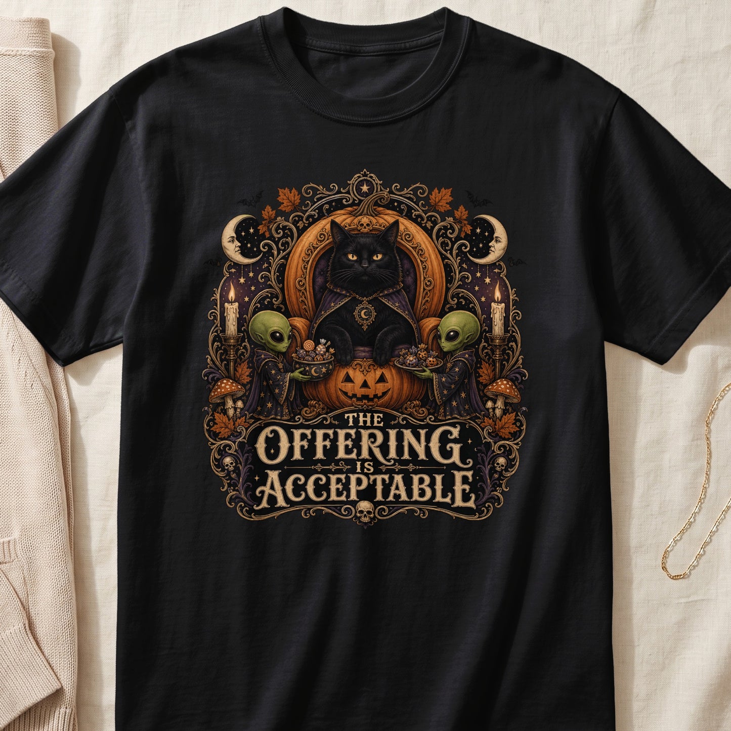 Black t-shirt graphic with black cat, aliens, pumpkin, text "The Offering Is Acceptable".