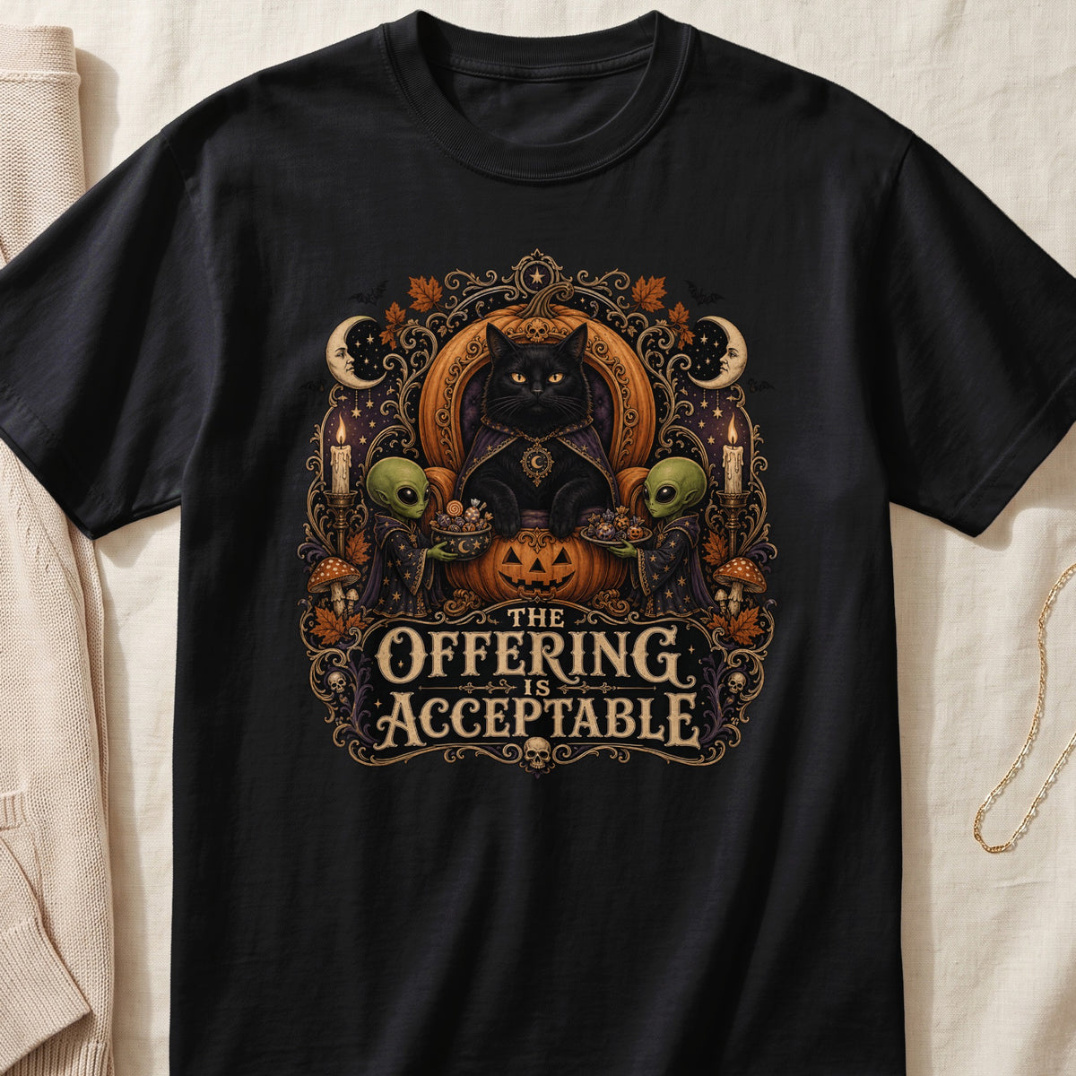 Black t-shirt graphic with black cat, aliens, pumpkin, text "The Offering Is Acceptable".