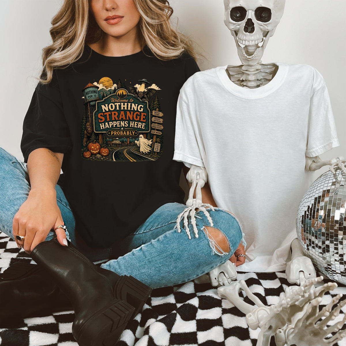 Black t-shirt with "Welcome to Nothing Strange Happens Here Probably" text and Halloween graphics.