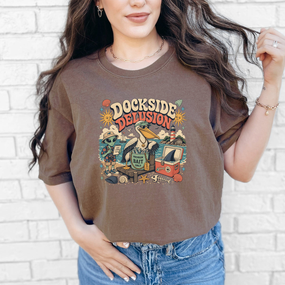 Graphic t-shirt with "DOCKSIDE DELUSION" text, alien, pelican, and fishing items.