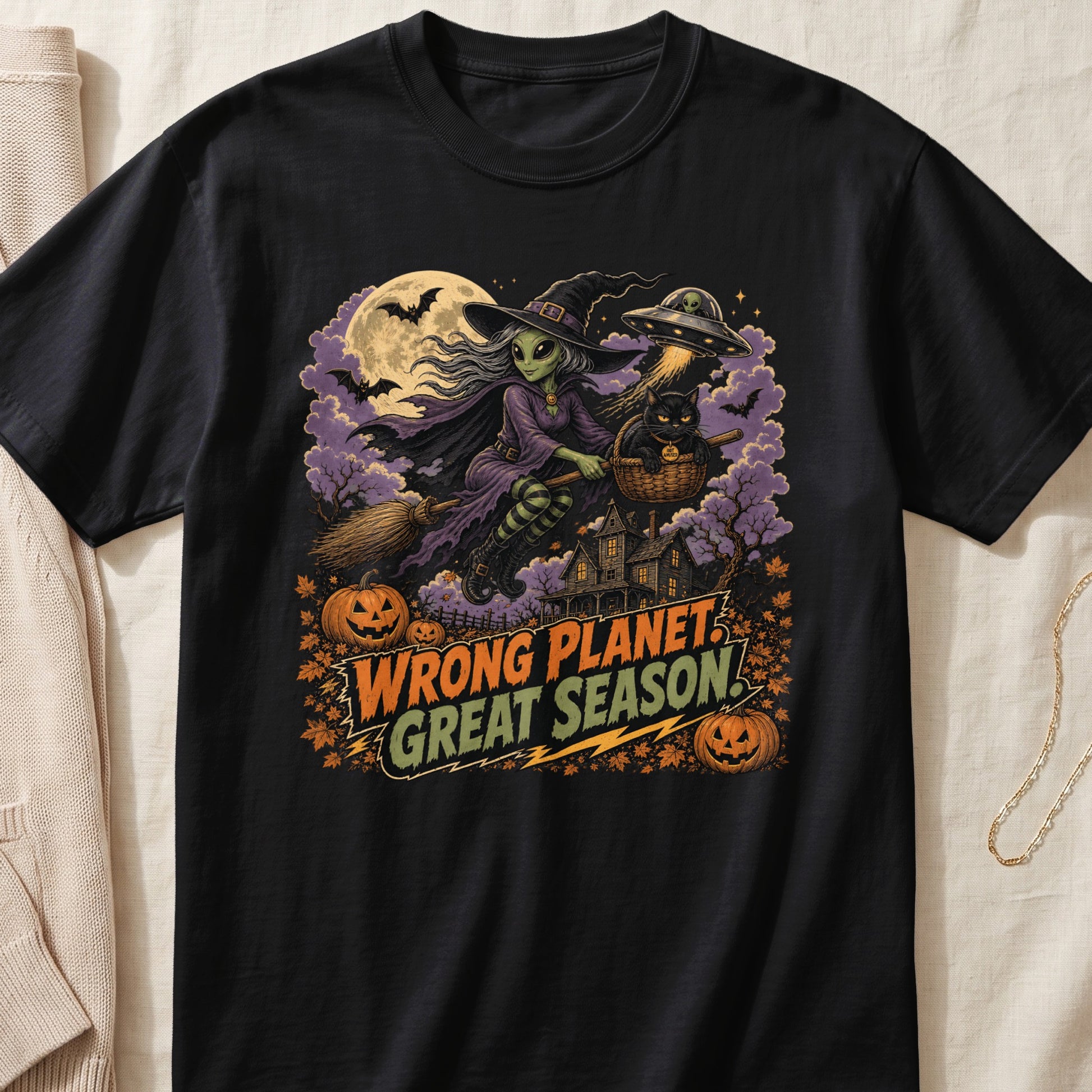 Alien witch flies broom with cat, UFO, and text "WRONG PLANET GREAT SEASON!"