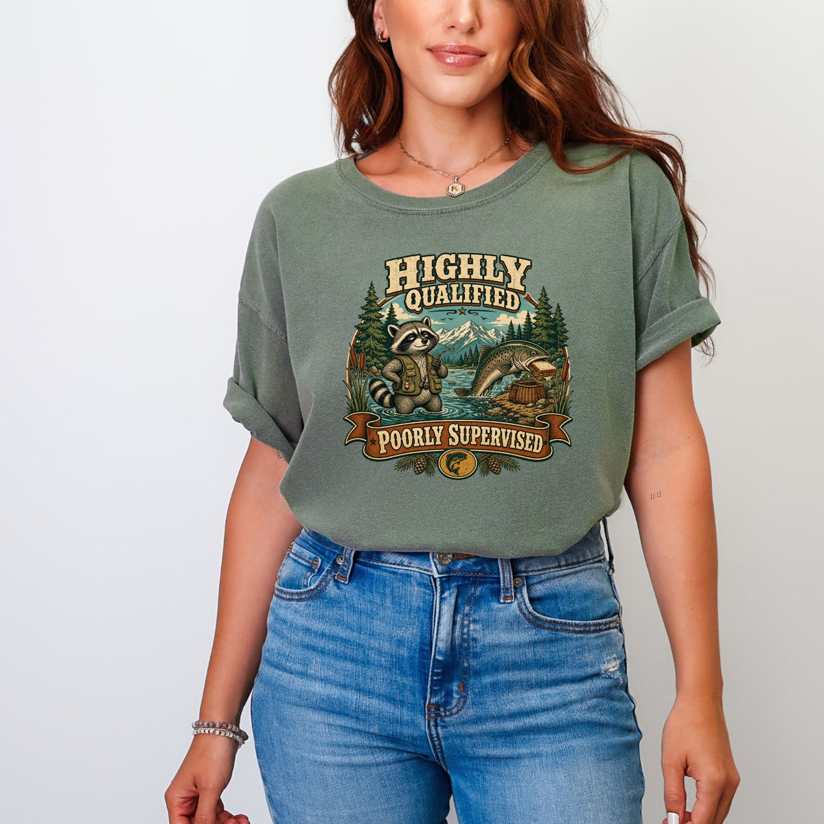 T-shirt graphic with raccoon fishing, fish, and text "Highly Qualified Poorly Supervised".