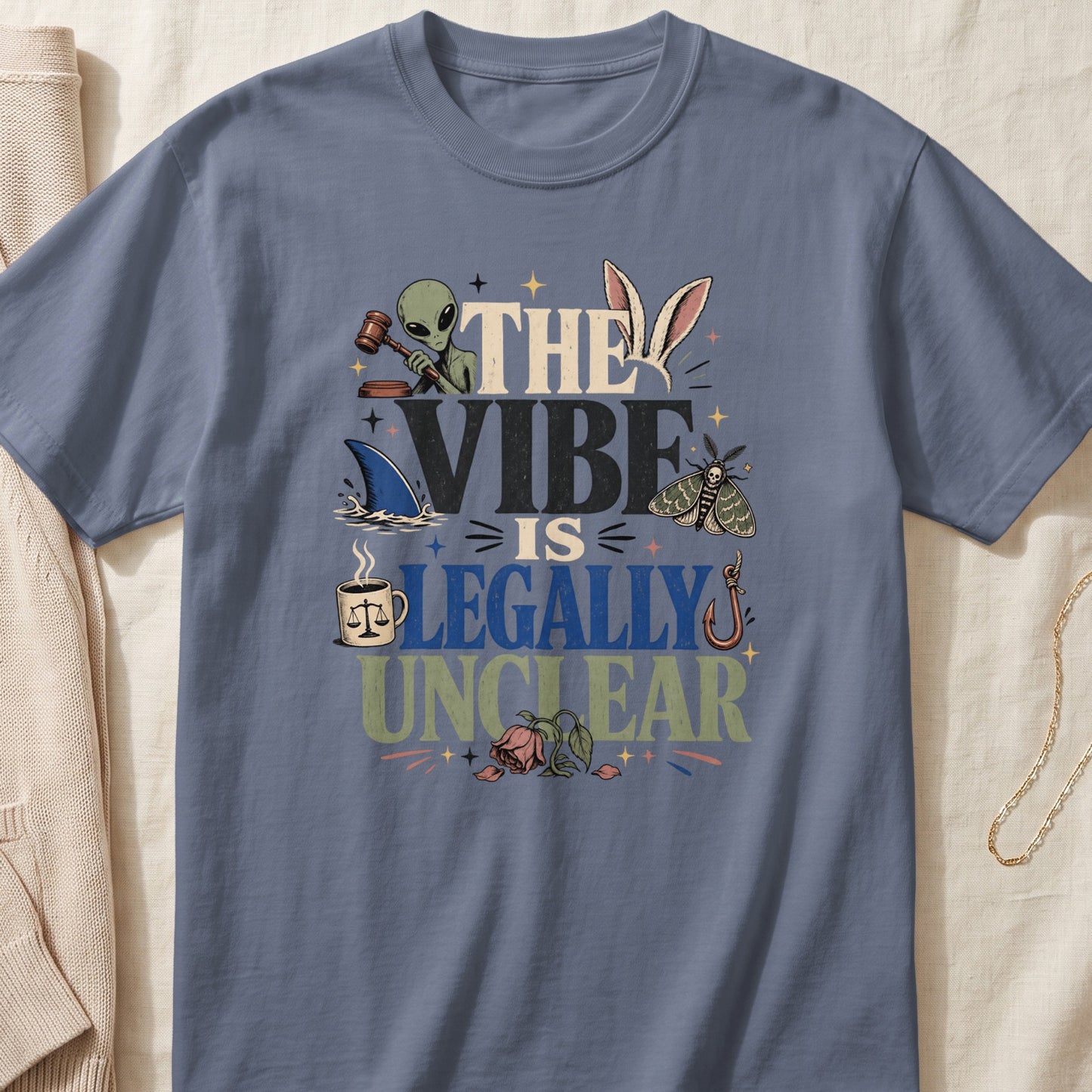 The vibe is legally unclear graphic tee with alien, shark, moth, and legal imagery.