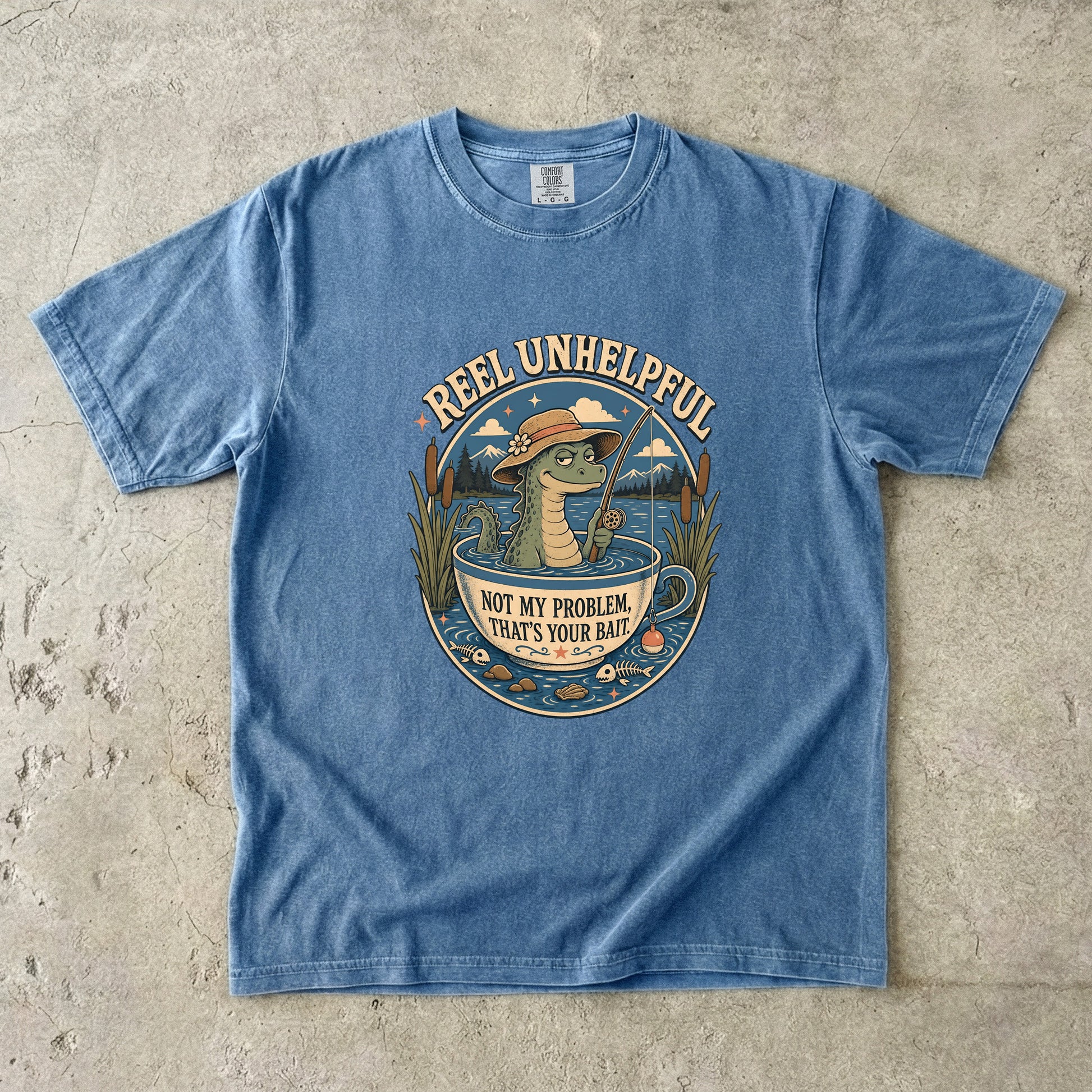T-shirt with graphic of alligator in a teacup fishing, text "REEL UNHELPFUL" and "NOT MY PROBLEM, THAT'S YOUR BAIT."
