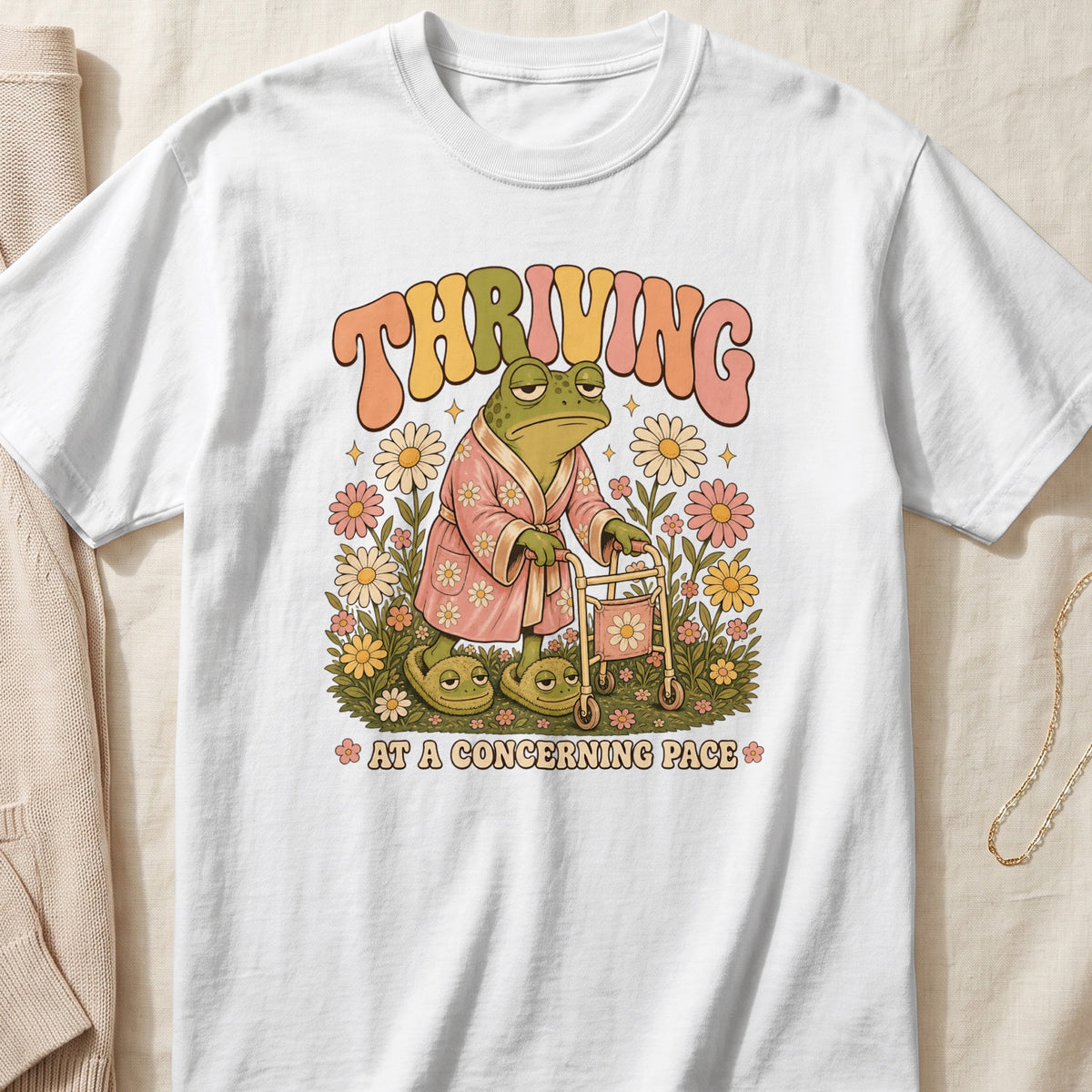 Frog in bathrobe and slippers with walker, text "THRIVING AT A CONCERNING PACE".