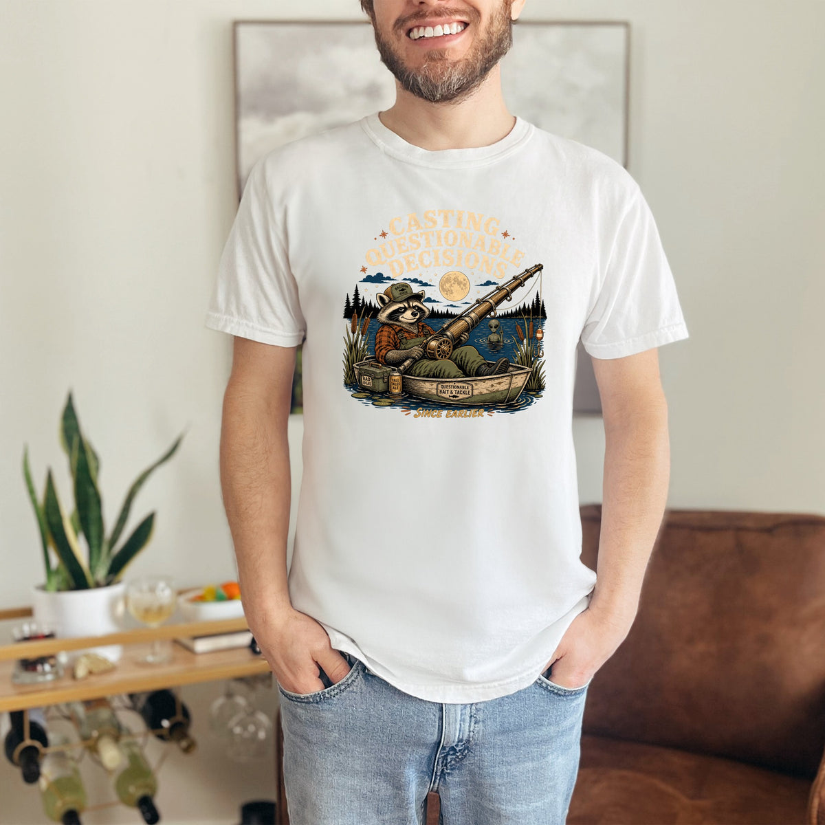 White t-shirt with raccoon fishing graphic, "Casting Questionable Decisions" text.