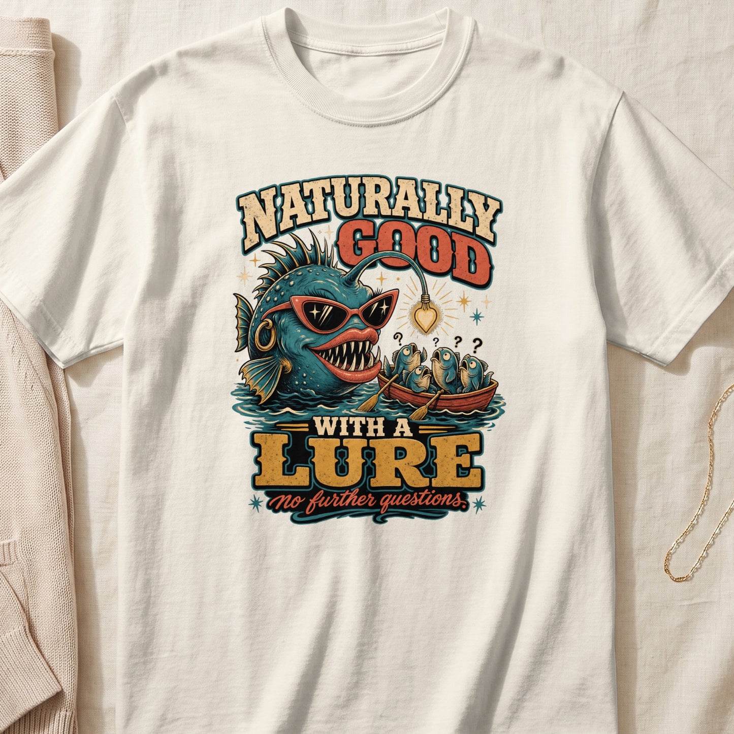 T-shirt graphic: "Naturally Good With A Lure" with anglerfish and fish in a boat.
