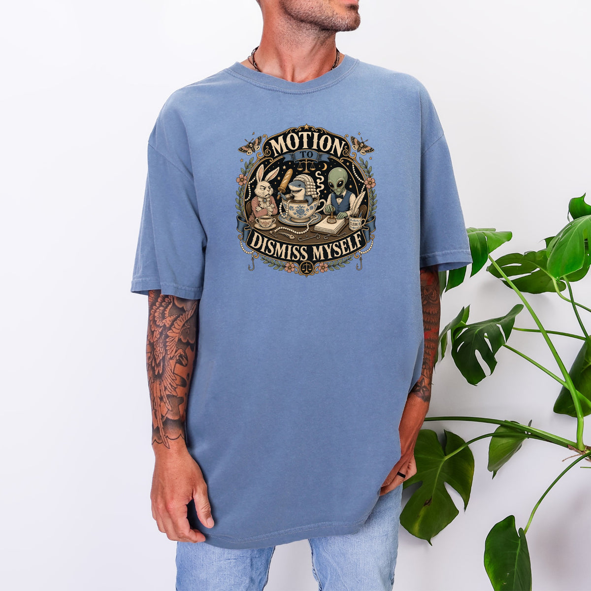 A man wearing a blue oversized t-shirt with a vintage-style graphic featuring animals and aliens.