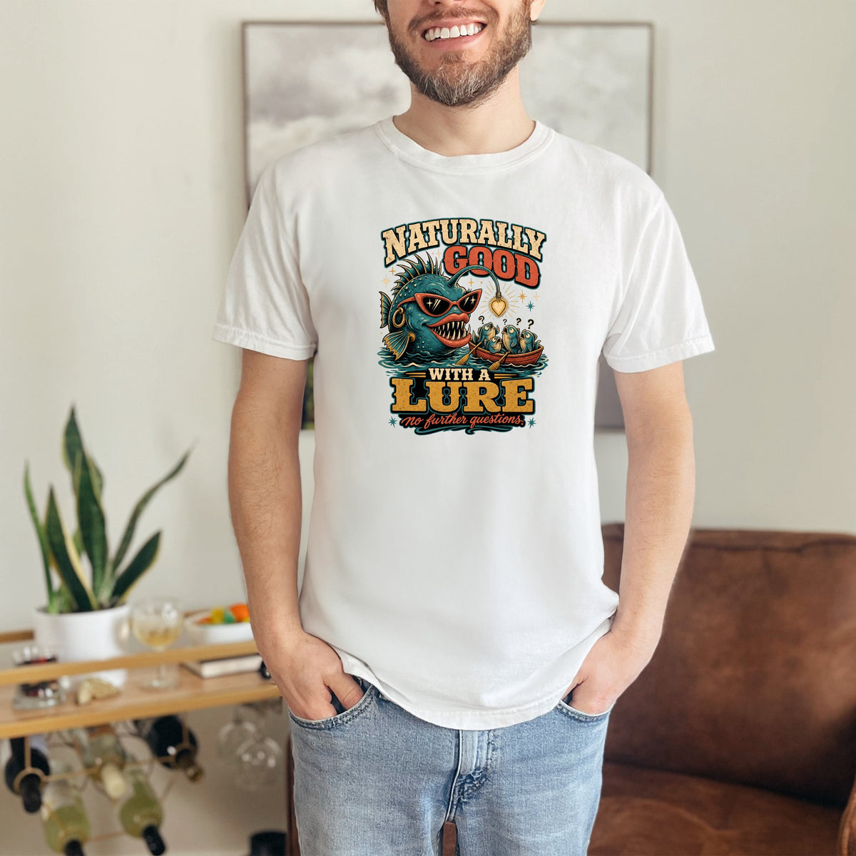 White t-shirt with a graphic of a fish in sunglasses saying "Naturally Good With A Lure".