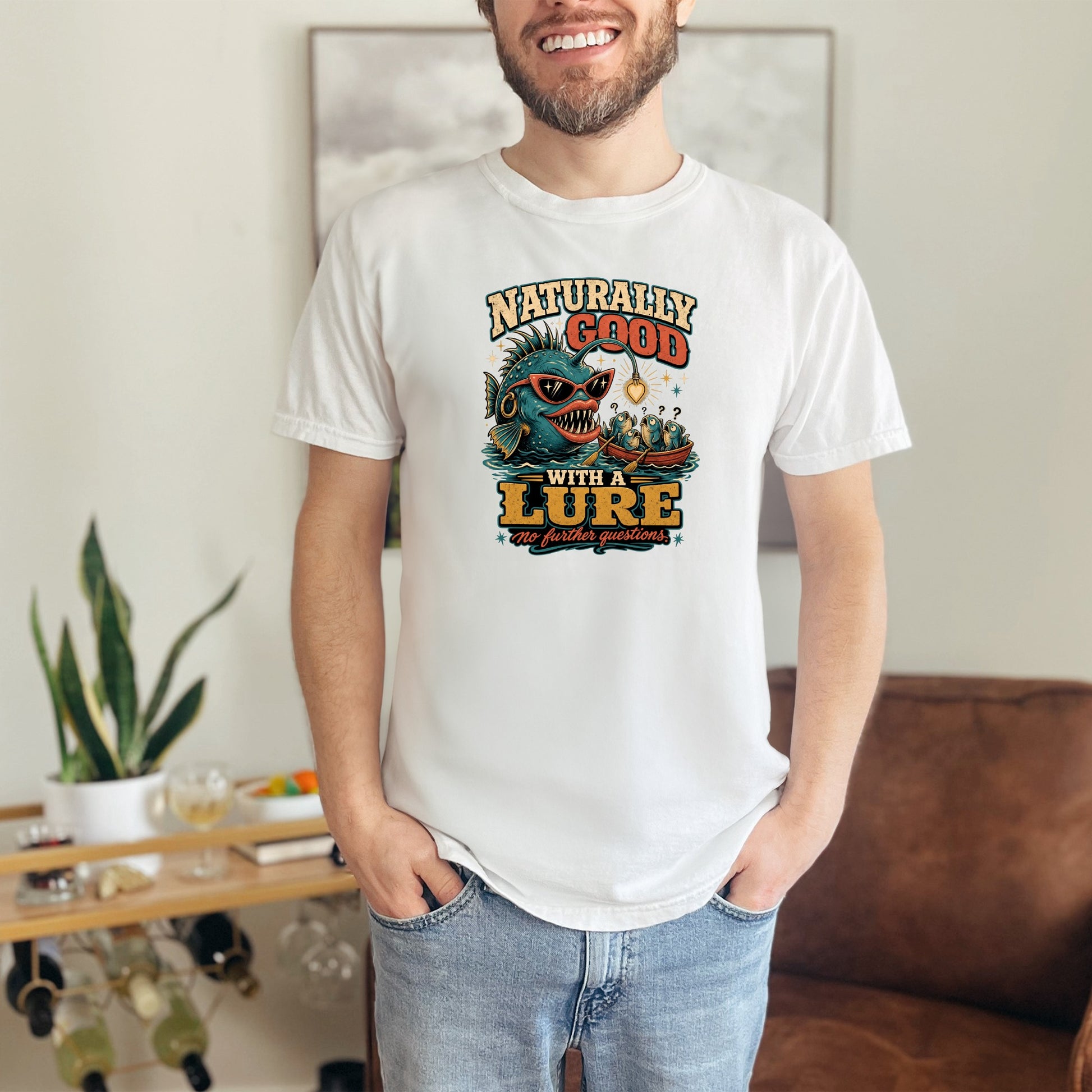 White t-shirt with a graphic of a fish in sunglasses saying "Naturally Good With A Lure".