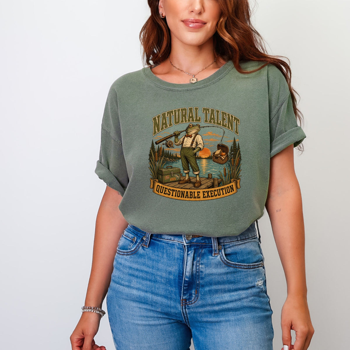 T-shirt graphic of a frog fishing on a dock with text "NATURAL TALENT QUESTIONABLE EXECUTION".